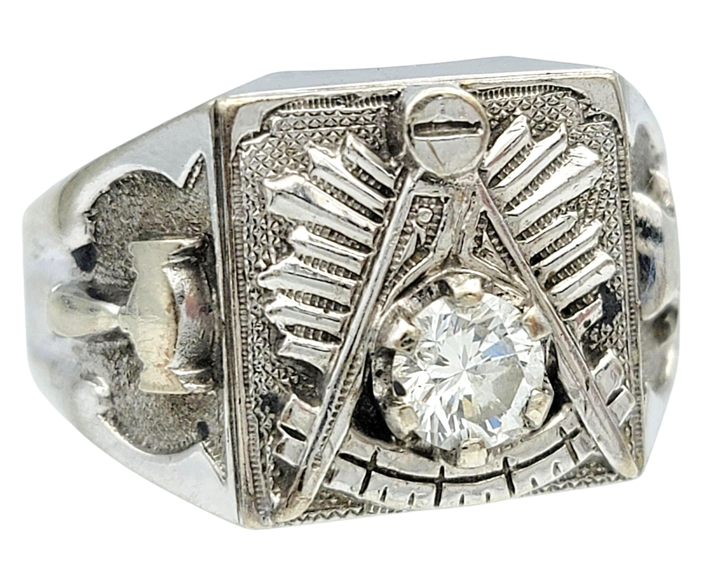 Cette audacieuse bague maçonnique en diamant présente un diamant rond de taille brillant mis en valeur dans une monture géométrique texturée. Le diamant brille d'un éclat accentué par sa teinte blanche brillante et le fort contraste du motif en