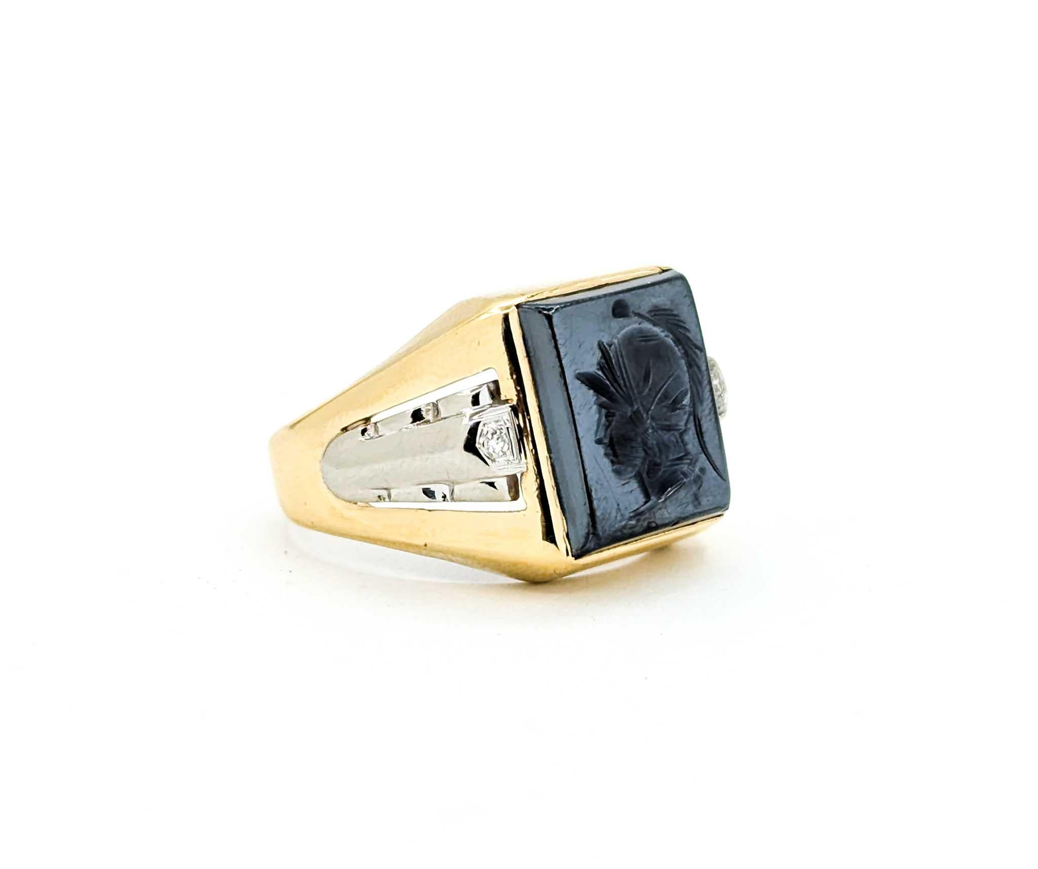 Handsome vintage men’s ring crafted in 10k yellow gold, showcasing a striking carved hematite intaglio of a Roman soldier. The bold rectangular hematite measures 16mm across, highlighted on each side by a single cut diamond accent, totaling