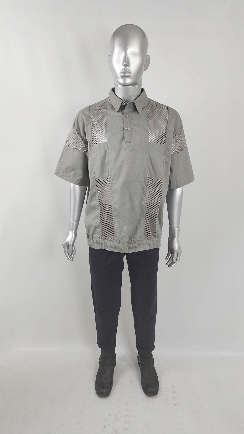 A stylish vintage men's shirt from the late 1980s / early 1990s. Made of grey cotton, it features see-through mesh panels, an oversized blouson fit, and short sleeves. Perfect for clubbing or a party.

Size: Marked D 52 / 54 - GB 42 / 44 which