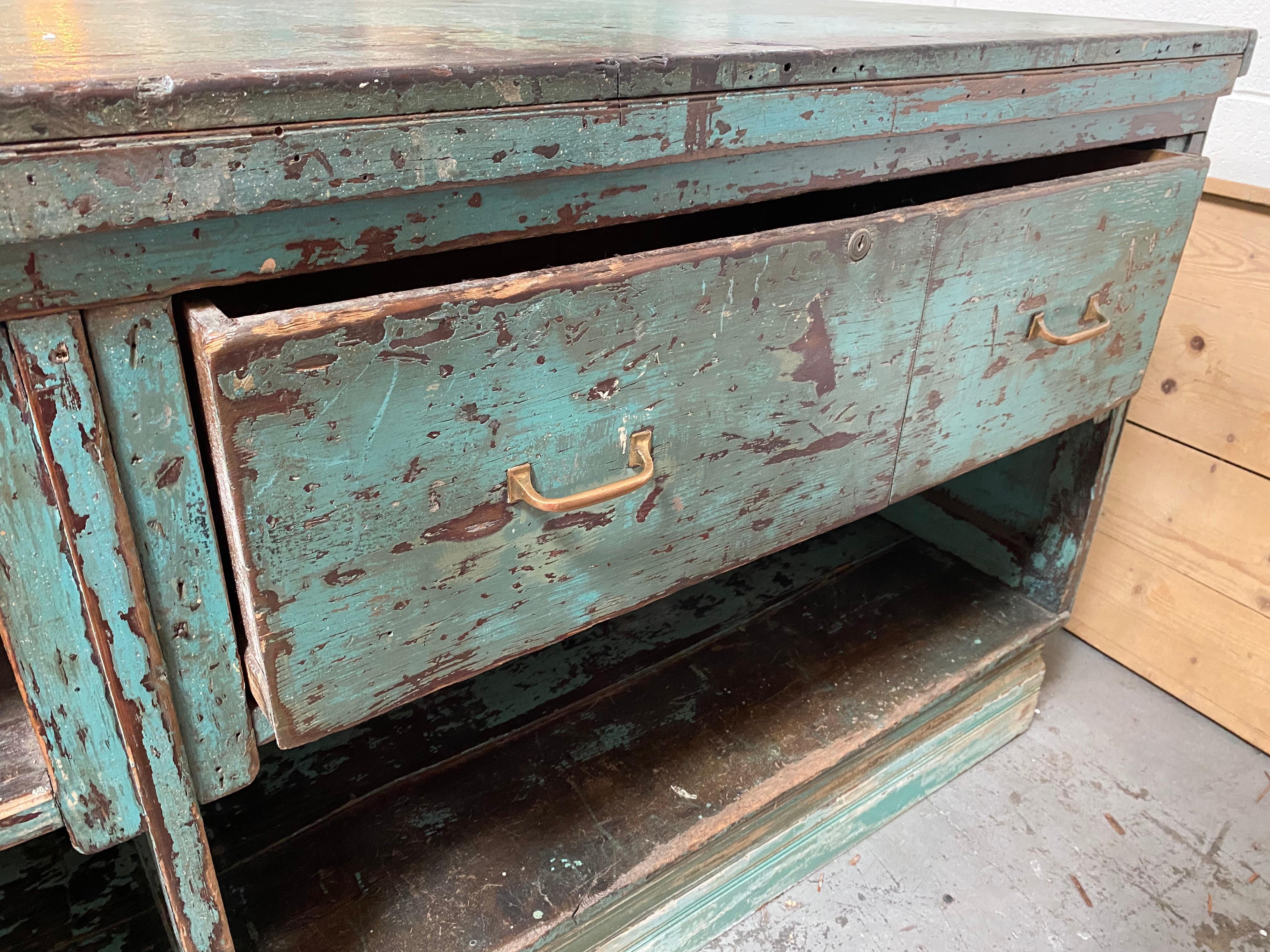 Vintage merchant’s shop counter in solid oak with storage and hammered tin details. This piece is massive and heavy! It would be an exceptional anchor for the right space as an island, countertop, or cash-wrap. Two hammered tin plates adorn the