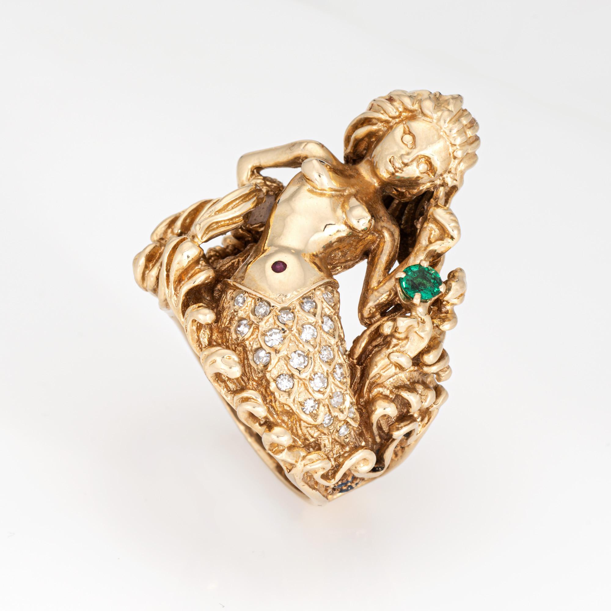 Finely detailed vintage mermaid ring crafted in 14 karat yellow gold (circa 1960s to 1970s). 

Diamonds total an estimated 0.12 carats (estimated at I-J color and SI1-I1 clarity). One emerald measures approx. 4mm. Sapphires total an estimated 0.10