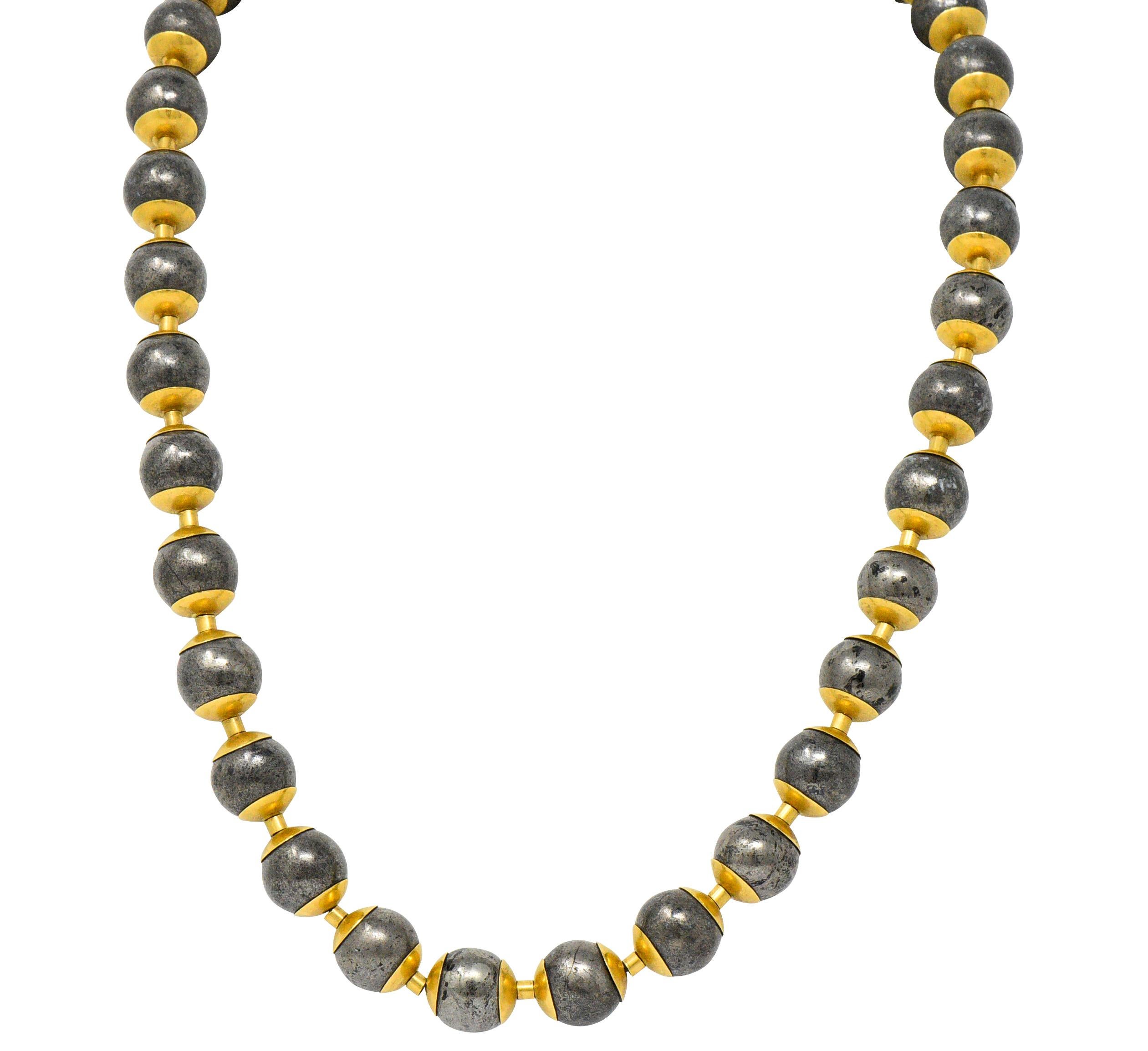 Link style necklace comprised of round metallic beads measuring approximately 11.6 to 12.4 mm

With excellent metallic luster and unique surface mottling

Each bead is framed by polished gold endcaps and separated by gold, barrel shaped, spacer