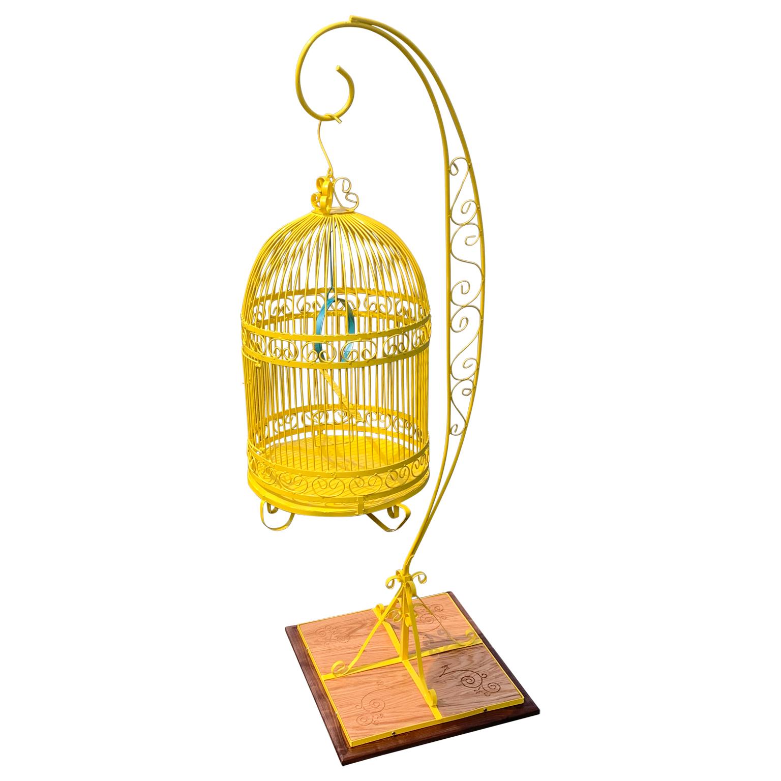 Vintage metal birdcage on decorated wooden stand. The birdcage and stand is newly powder-coated in bright sunshine yellow. The metal ring inside the birdcage is powder-coated in a turquoise color.