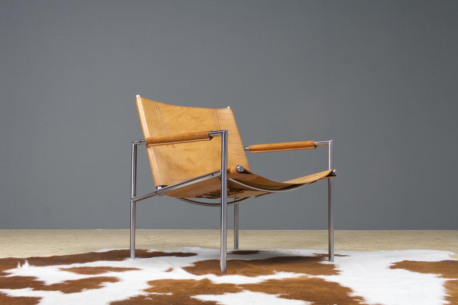 A vintage and original SZ02 leather lounge chair by Dutch designer Martin Visser designed for ’t Spectrum in 1965. The chair is executed in a brown /tan colored saddle leather and has leather upholstered armrest. The piece has great detailing of the