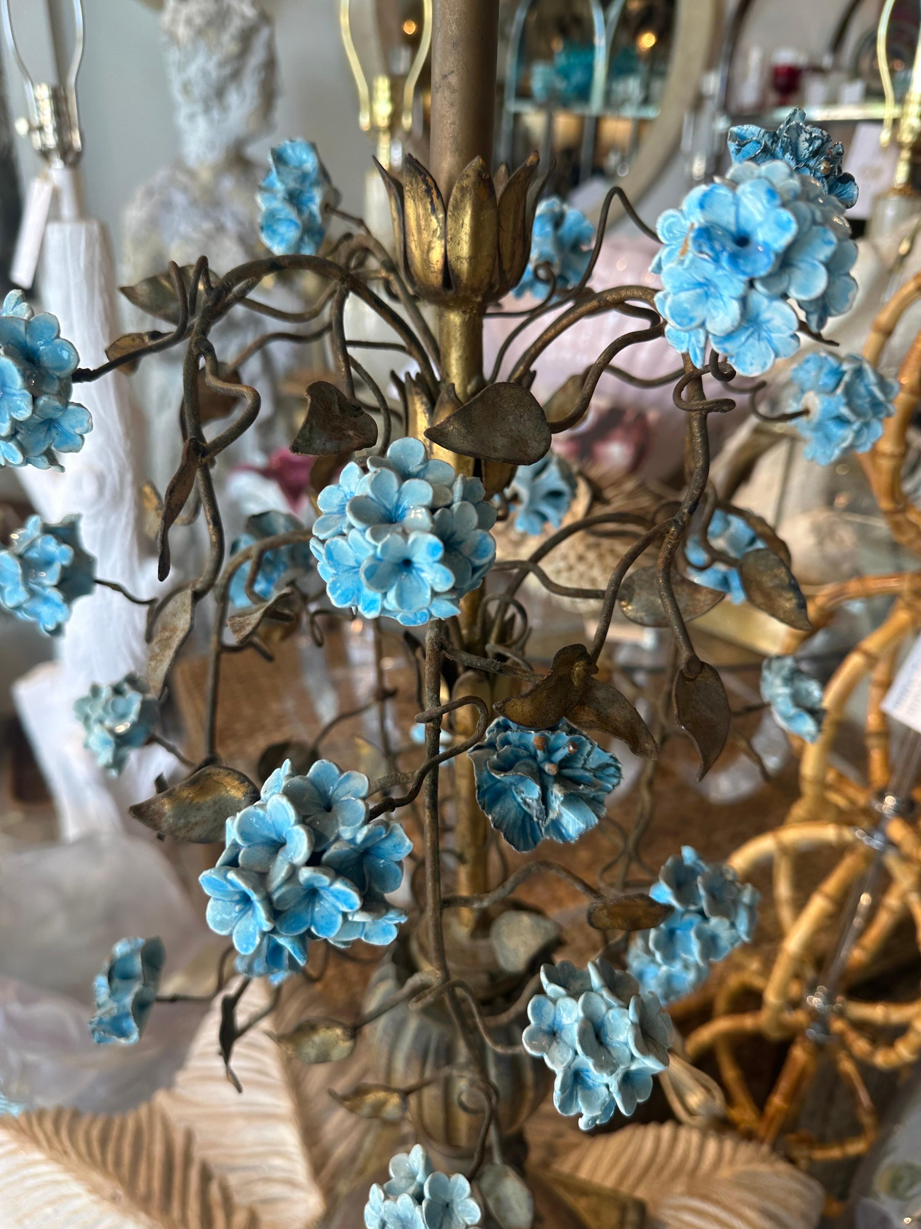 Beautiful 1940s metal tole Italian table lamp with blue porcelain hydrangea flowers. Chippy patina urn base. This lamp has been newly wired, clear cord, 3 way brass sockets. Dimensions: 37 H (to top of brass finial) x 30 H (to top of lamp socket) x