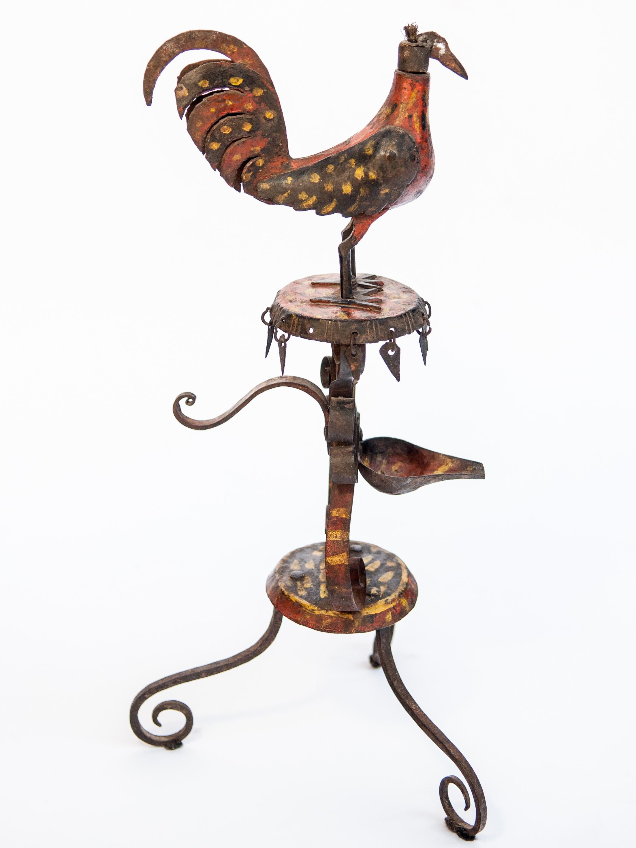 Vintage metal oil lamp rooster motif original color, Rural Nepal, mid-20th century.
Charming Folk Art lamp from the hills of west central Nepal. It was worked by a village blacksmith, fashioned of wrought iron using basic tools, and then painted.