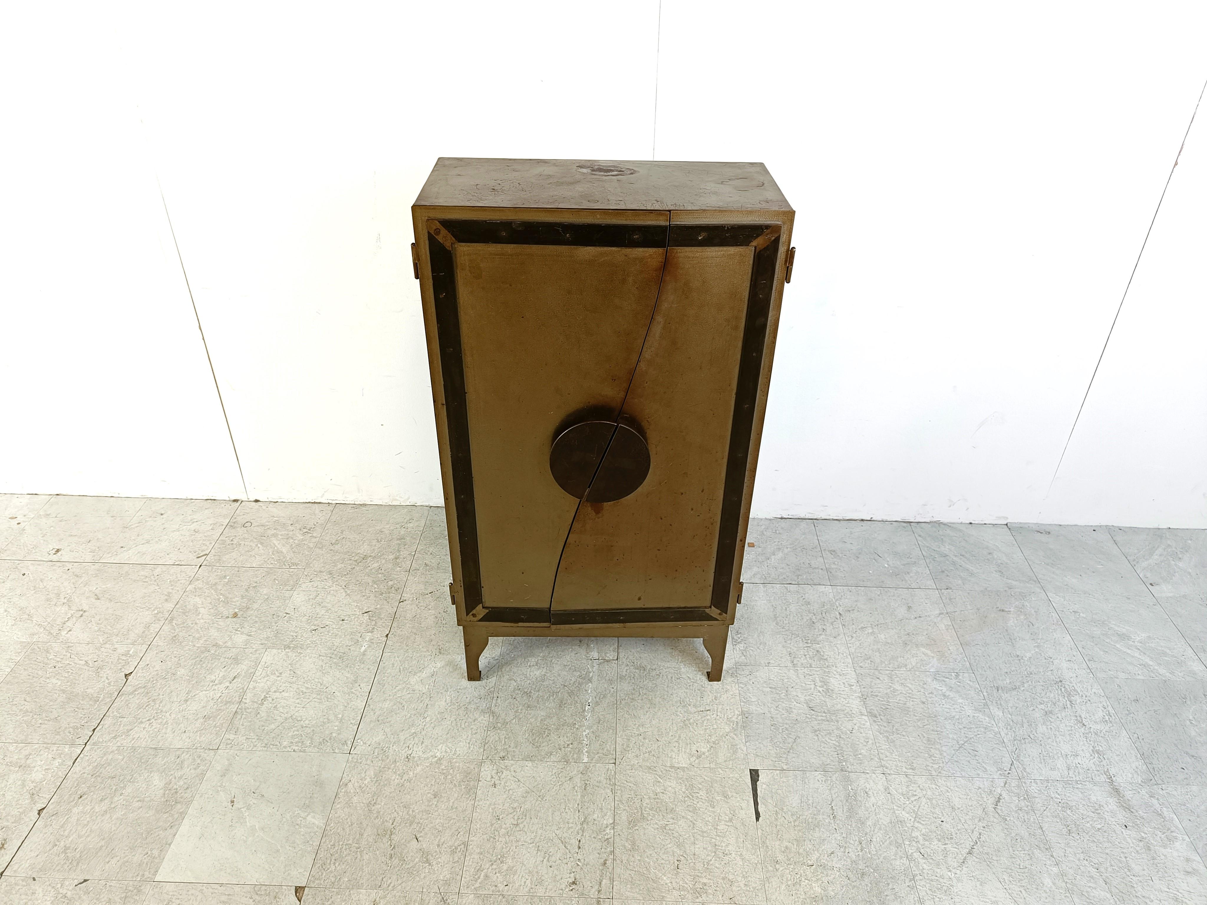 Vintage steel industrial cabinet with a touch of design.

This beautifully weathered and patinated cabinet has a mix of industrial and design.

Beautiful cut metal doors with designed handles revela a three shelf storage space.

This cabinet has