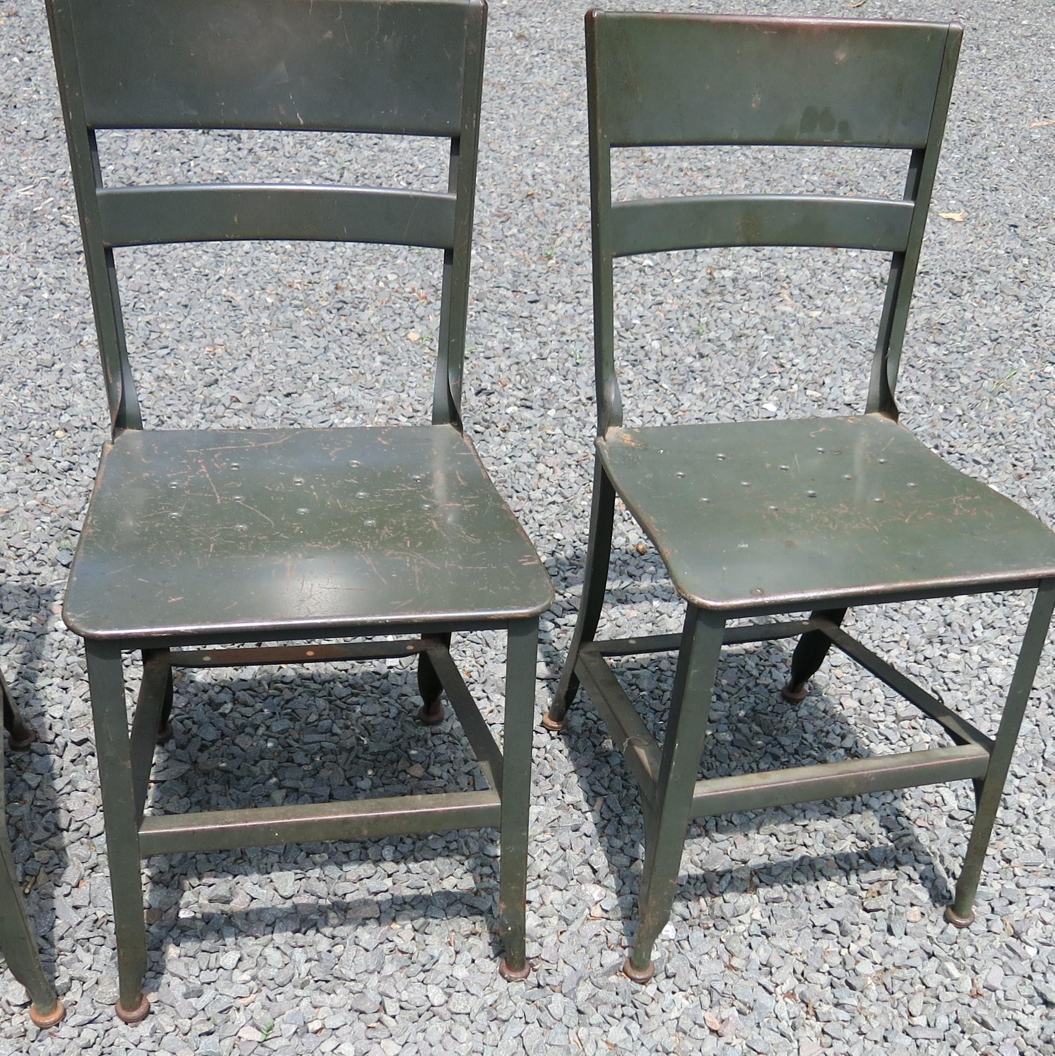 Four vintage metal Toledo chairs with distressed paint. There is paint loss and rust on the feet. They are 15.25