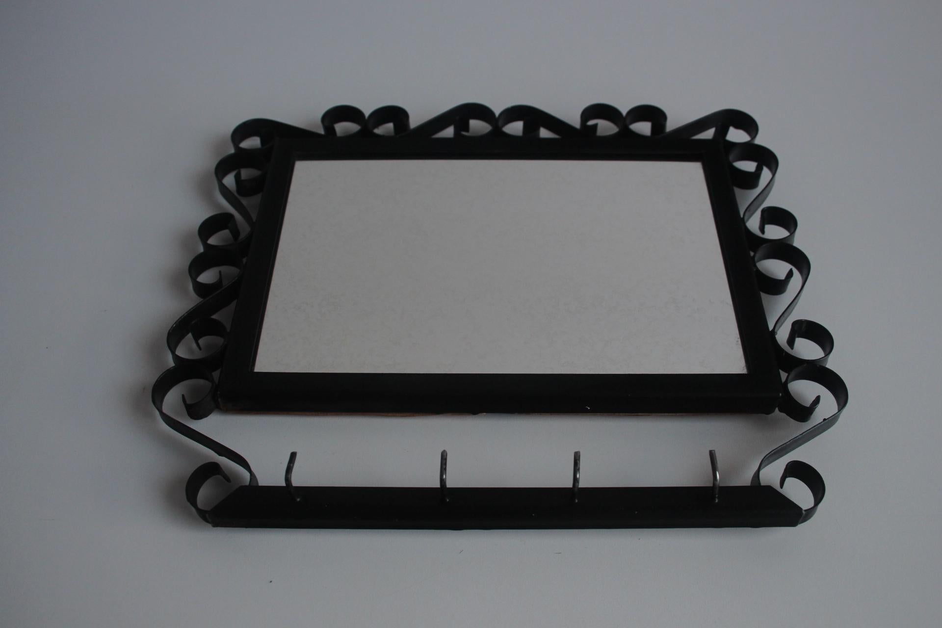 Elegante specchio da parete con cornice in metallo e ornamenti decorativi. Lo specchio è dotato di una pratica barra con ganci ideale per chiavi o piccoli oggetti.
Un accessorio elegante
Lo specchio presenta una patina di invecchiamento e un po' di