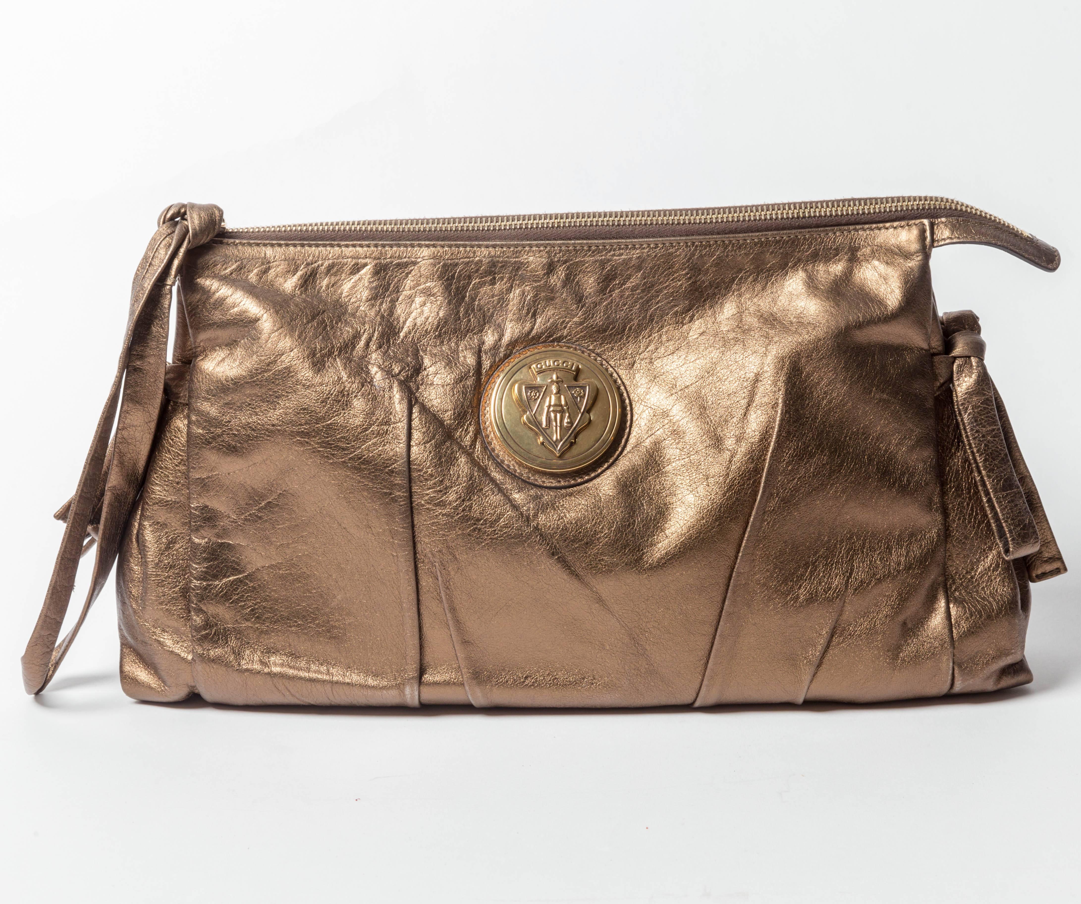 Large Vintage Gucci Clutch in Metallic Bronze Leather with Large Gold Gucci Medallion
Zip Closure
One interior zip pocket as well as a flap pocket for phone
Small mark to interior fabric lining
Exterior is in excellent condition