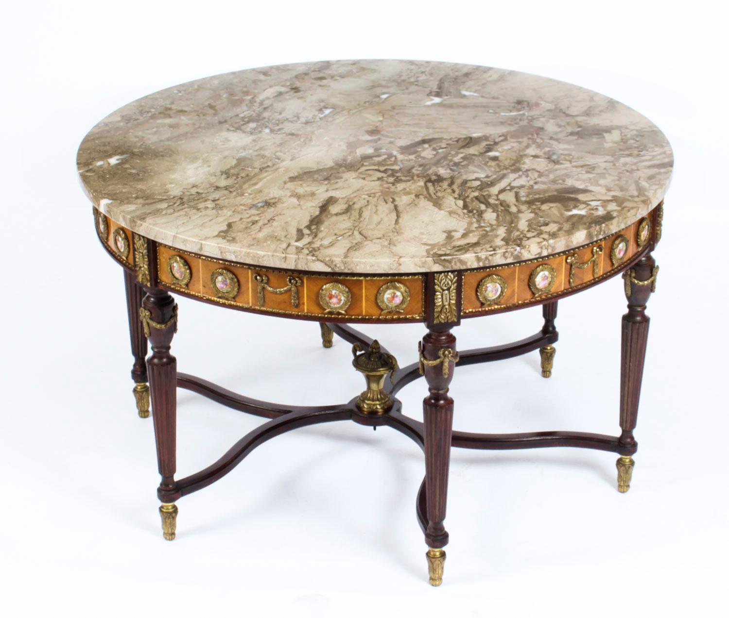 This is an exquisite ormolu-mounted Meuble Francais Louis Revival walnut marble top coffee table dating from the mid-20th century.

This wonderful coffee table is circular in shape and has four elegant and stylish fluted tapering legs. The frieze
