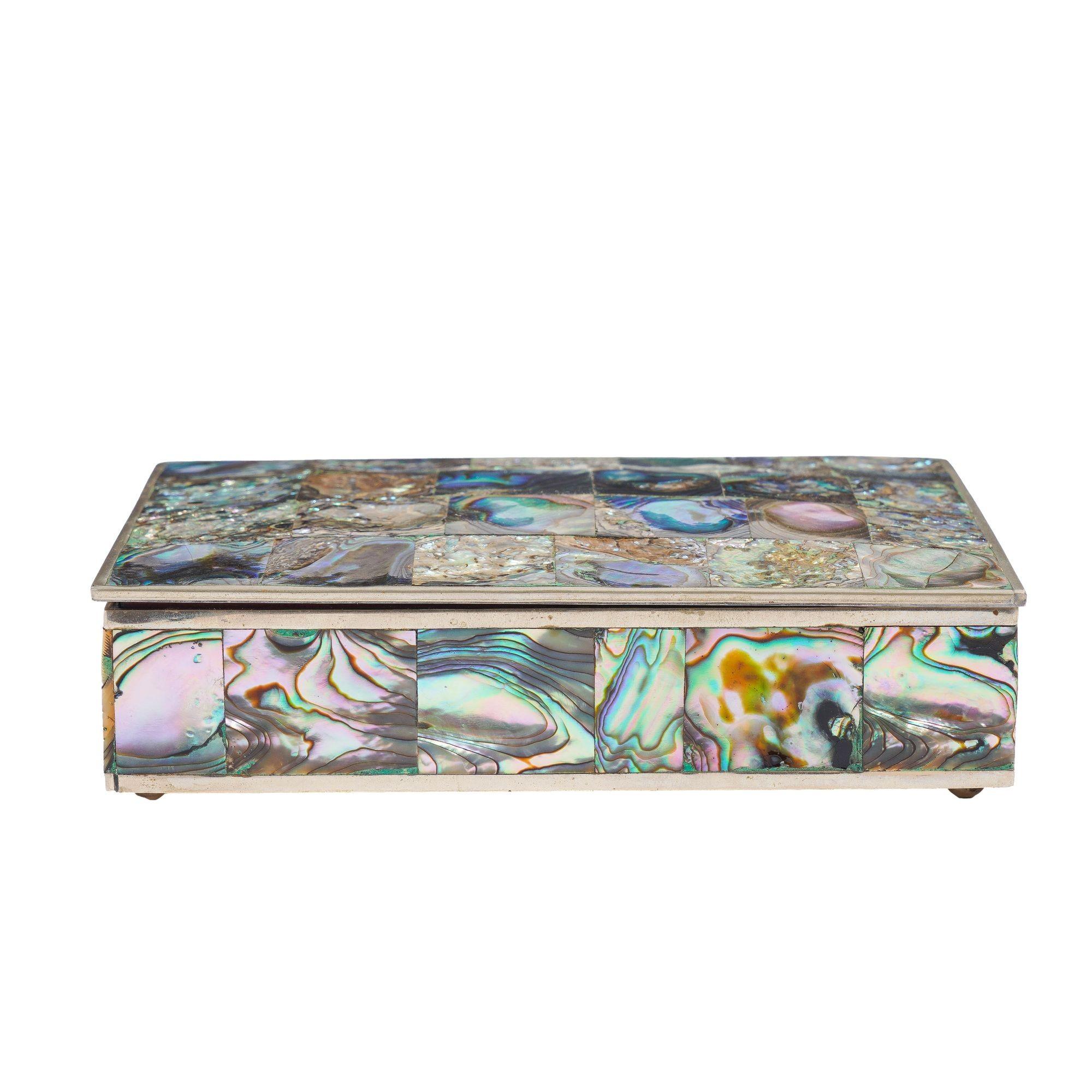 Scatola rettangolare con coperchio a cerniera in metallo abalone e alpaca con rivestimento interno in mogano. Il coperchio è dotato di una cerniera per pianoforte e l'esterno della scatola è intarsiato con quadrati di conchiglia abalone a