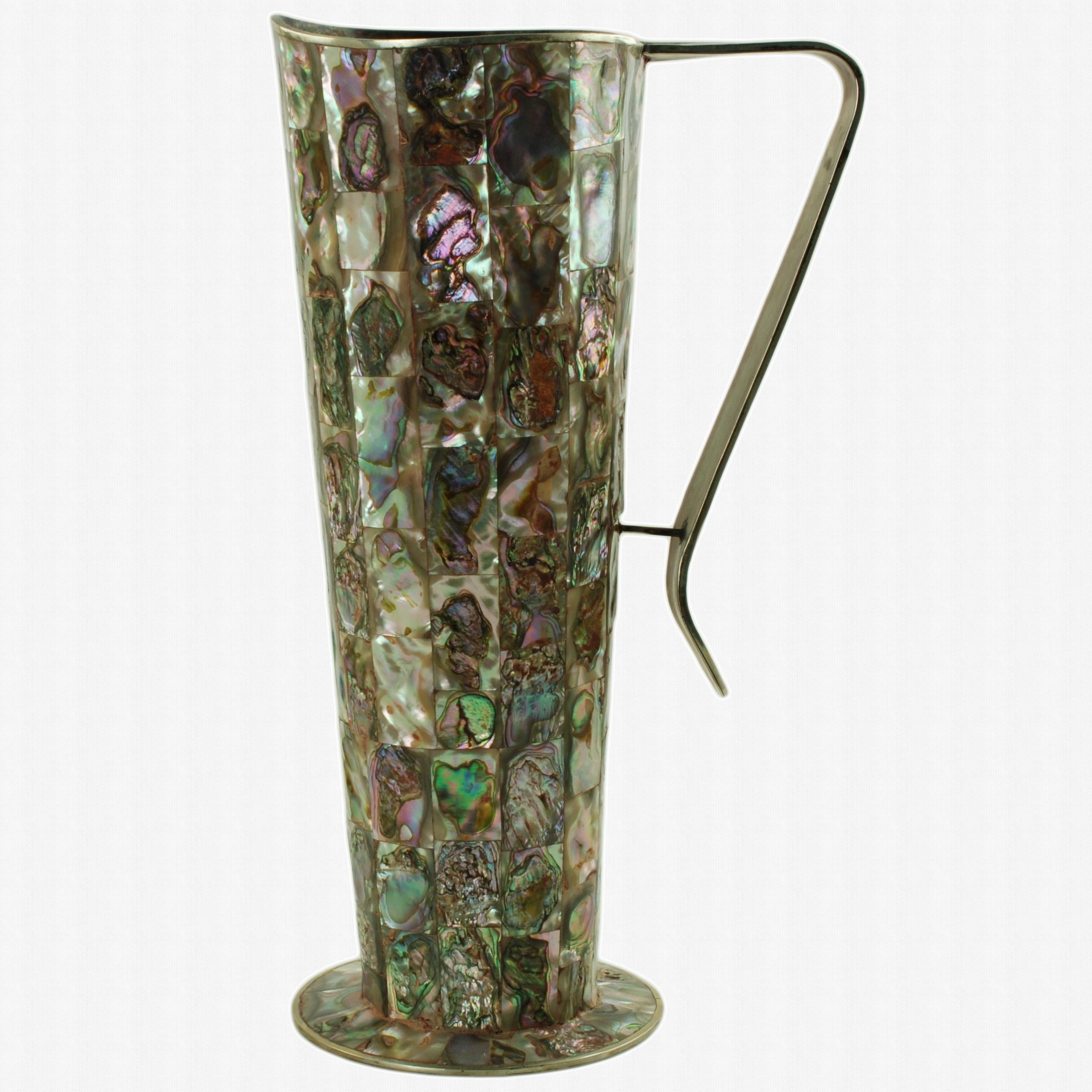 Queste splendide brocche in alpaca da 10,75 pollici sono state realizzate in Messico e presentano una decorazione tradizionale all-over sotto forma di file intarsiate di piastrelle di abalone. Le brocche hanno piedi a piattaforma di 4 pollici di