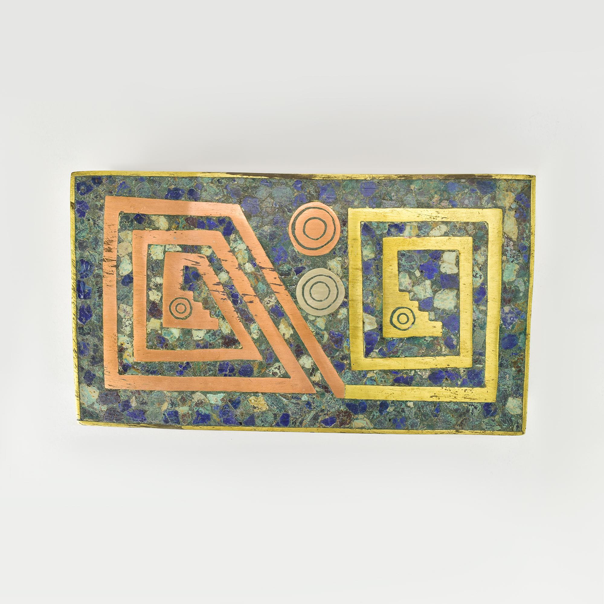 Questo squisito cofanetto d'epoca proveniente dal Messico presenta un mosaico di pietre dalla superficie riccamente strutturata, che combina profonde sfumature di blu e verde. L'ornamento geometrico è realizzato in rame, argento e ottone, formando