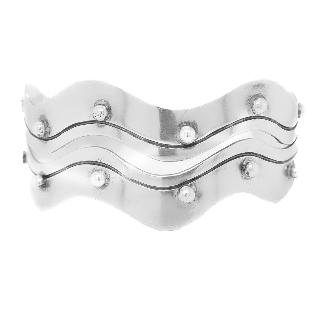 A fine silver cuff bracelet.

By Citlali.

In sterling silver.

In a cuff bracelet form with a wavy openwork line surrounded by decorative knops or rivets.

Marked to the interior of the bracelet with Citlali's maker's mark / 925.

Simply a