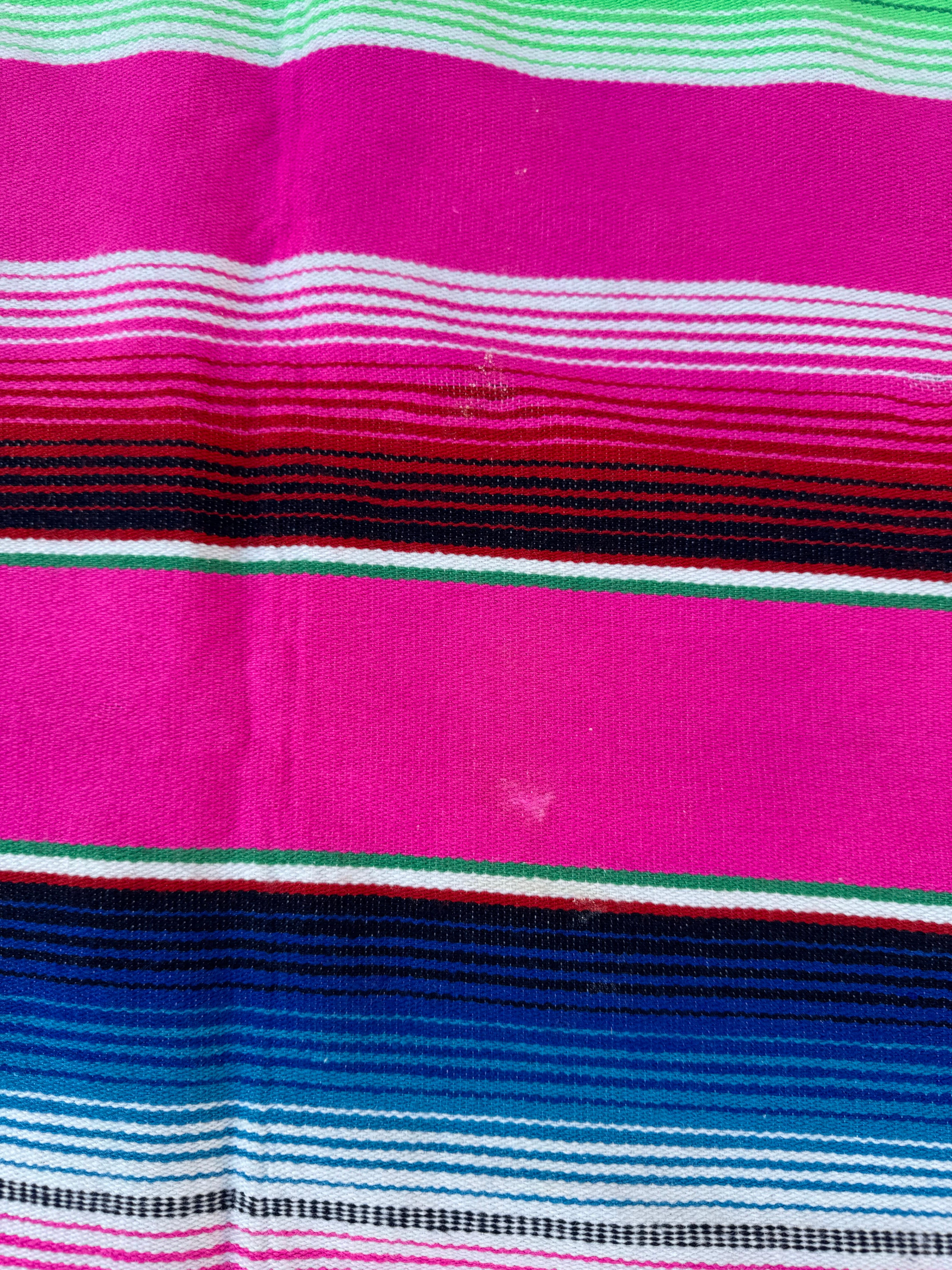 Aggiungi una vibrante esplosione di colore e tradizione al tuo spazio con questa coperta messicana vintage in serape. Con una larghezza di circa 55 pollici e una lunghezza di 82 pollici, questo splendido tessuto è caratterizzato da vivaci strisce