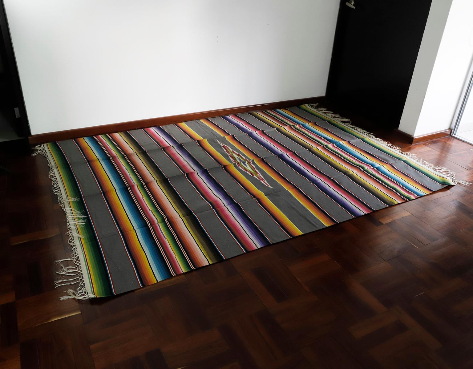 Circa 1940, we offer this finely hand crafted and vibrantly hued striped hand loomed wool serape from Mexico.