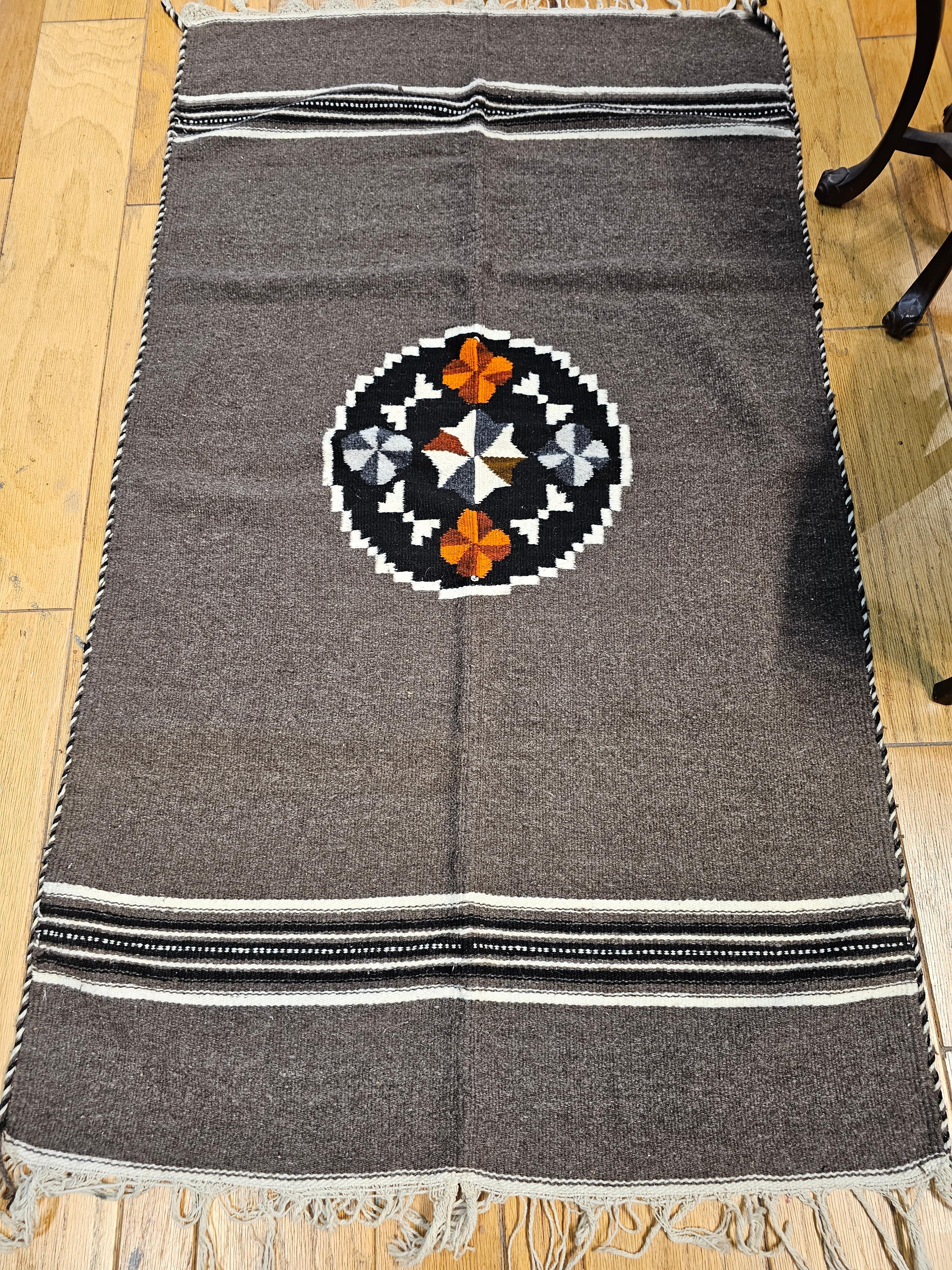 Vintage Mexican Serape Kilim Rug in Dark Gray/Chocolate Color. A beautiful Serape kilim rug was woven in Mexico in the 3rd quarter of the 1900s. The rug has a beautiful dark gray/chocolate color with stripes in the top and bottom of the kilim in