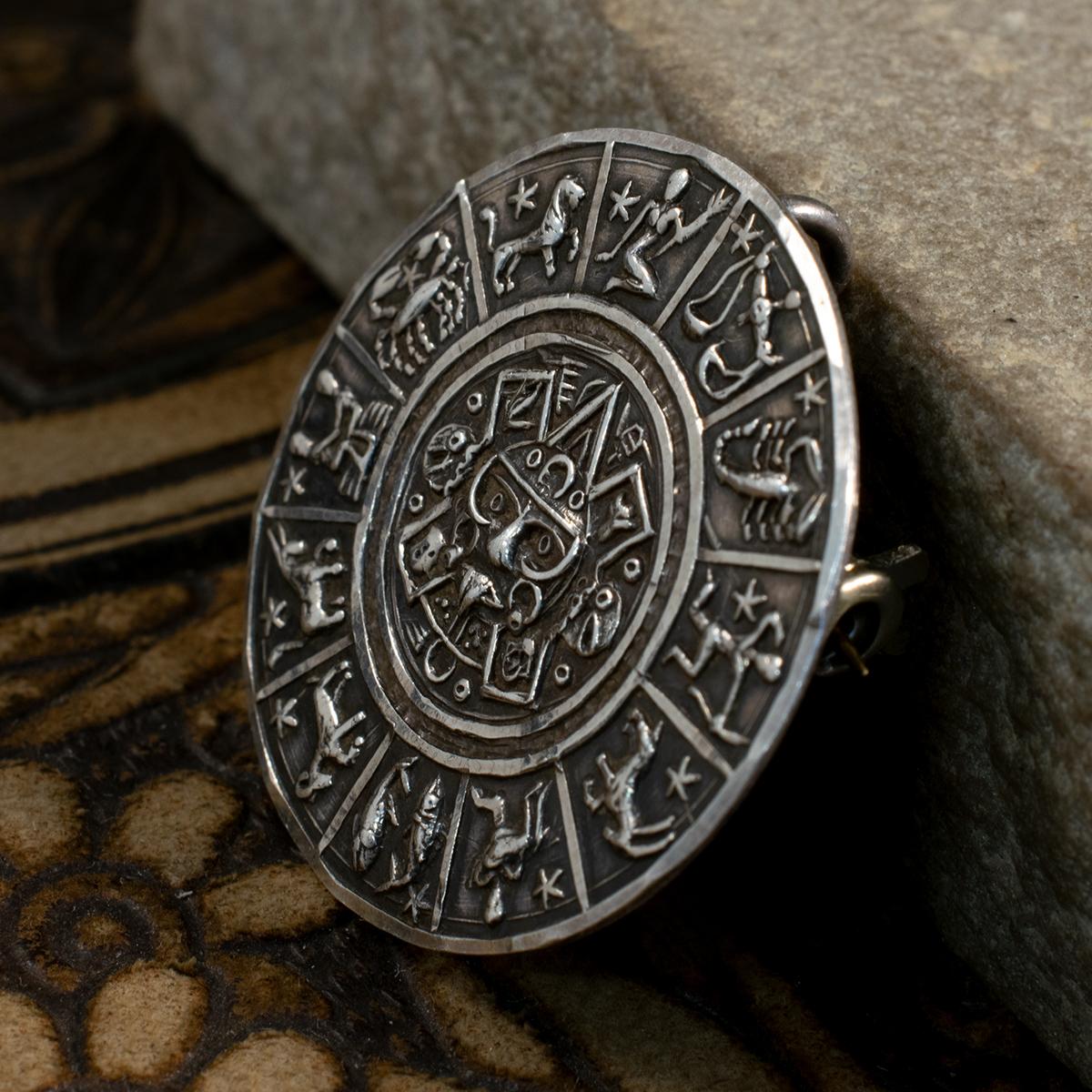 A Sterling Silver Brooch Pendant stamped on the reverse, Mexico and Sterling 925. The design on the brooch shows the 12 signs of the zodiac, each being intimately detailed and clear. In the centre is a Mayan or Aztec depiction of the sun all in a