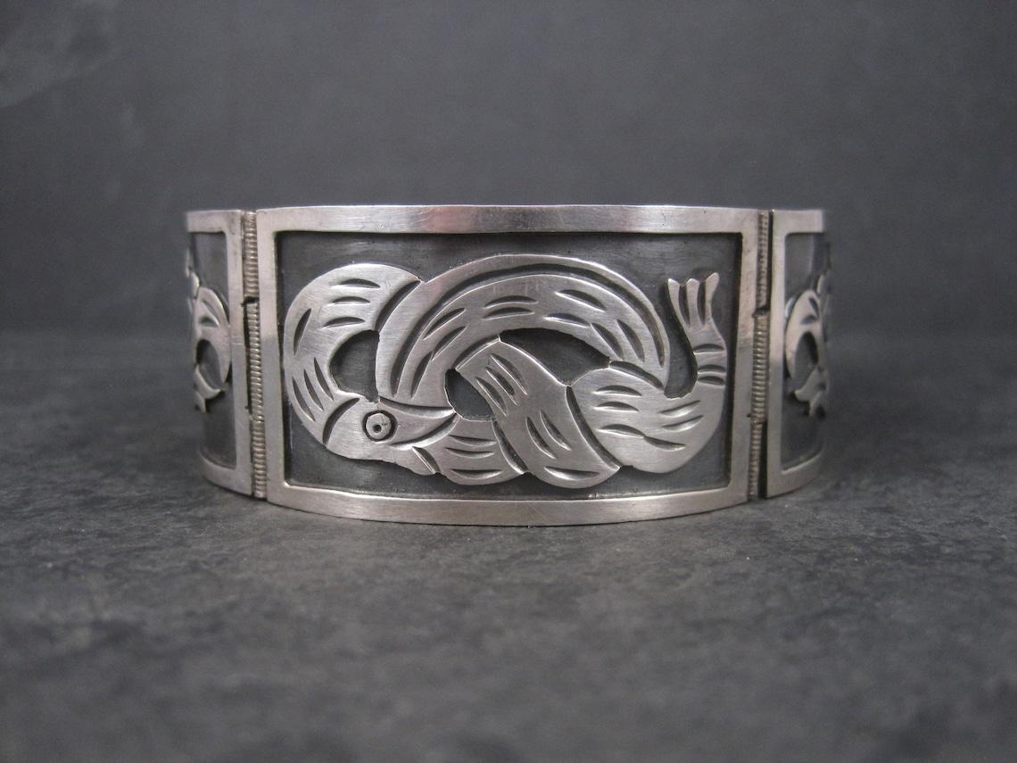 This gorgeous vintage panel bracelet is sterling silver.
It features a coiled snake and eagles heads in an overlay design.

Measurements: 1 inch wide
7 wearable inches
56.6 grams

Marks: Hecho en Mexico, Iguala, 925

Condition: Excellent