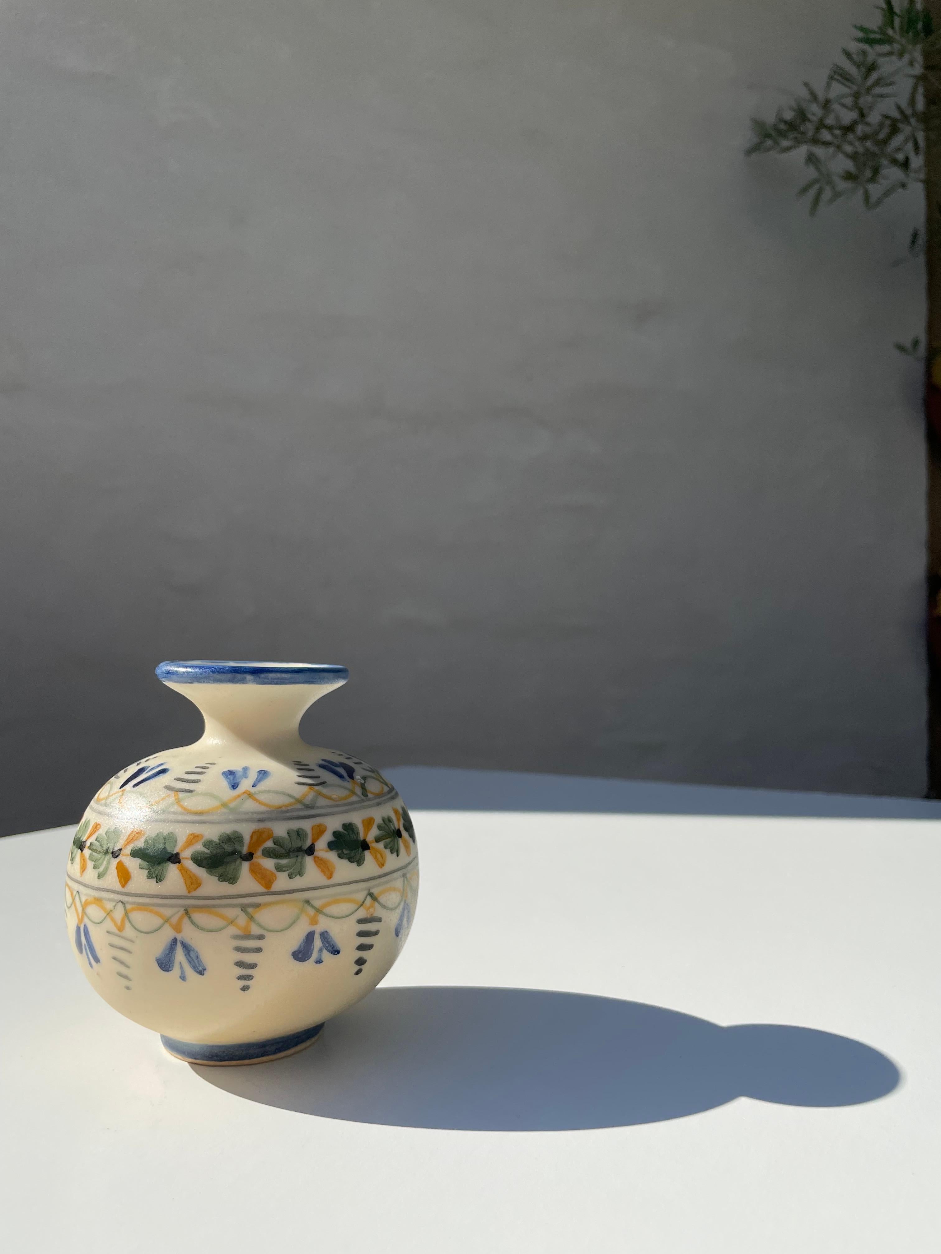 Handmade Mexican Talavera Mave ceramic vase delicately decorated by hand. Floral, organic decor in blue, green and dark yellow on a creamy light yellow colored base. Signed under base. Beautiful vintage condition. 
Mexico, early 20th century.