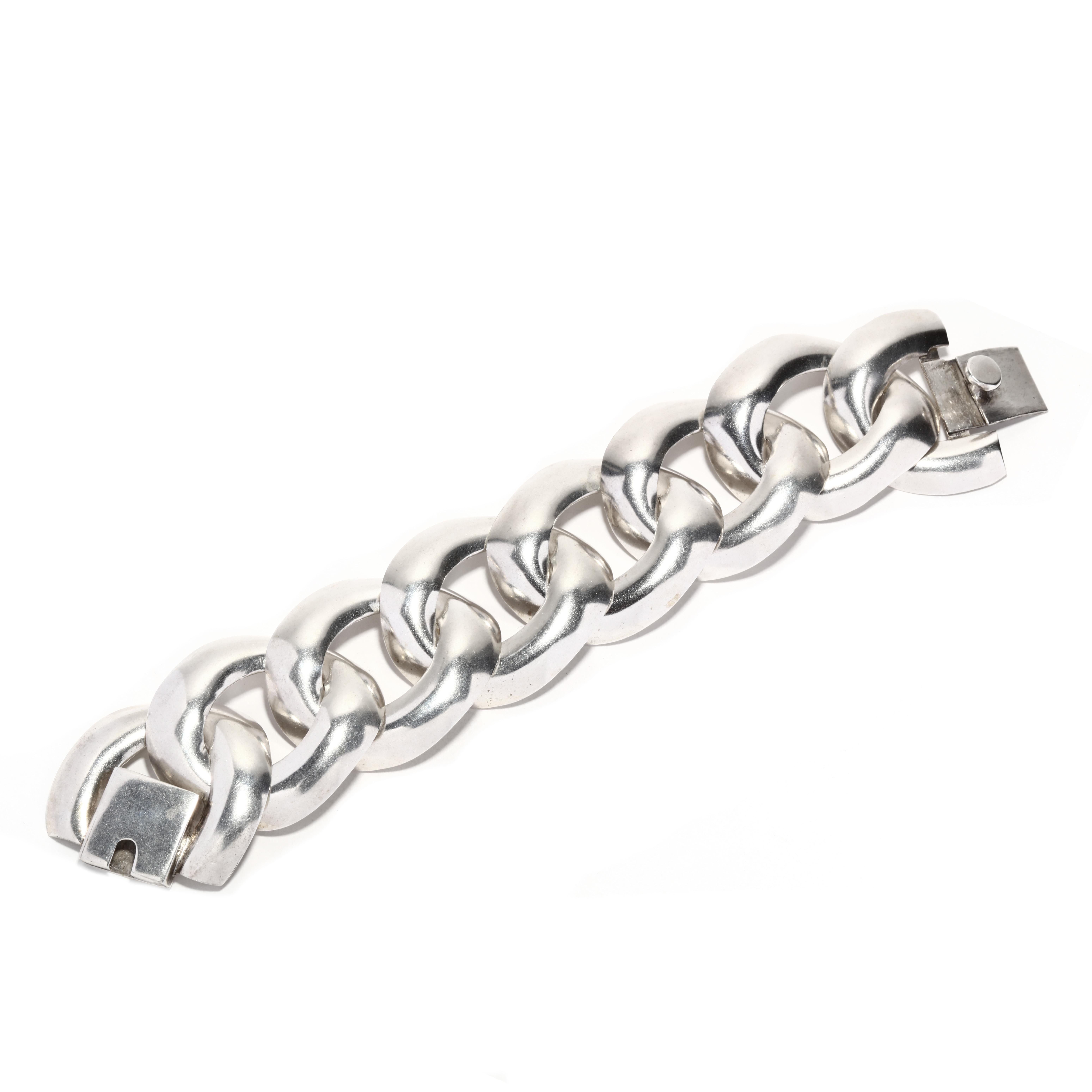 This vintage Mexican wide chain link bracelet demonstrates the unique style of Mexican silver craftsmanship. The sterling silver bracelet measures 7.5 inches in length and features a wide curb link design. This piece is a perfect addition to any