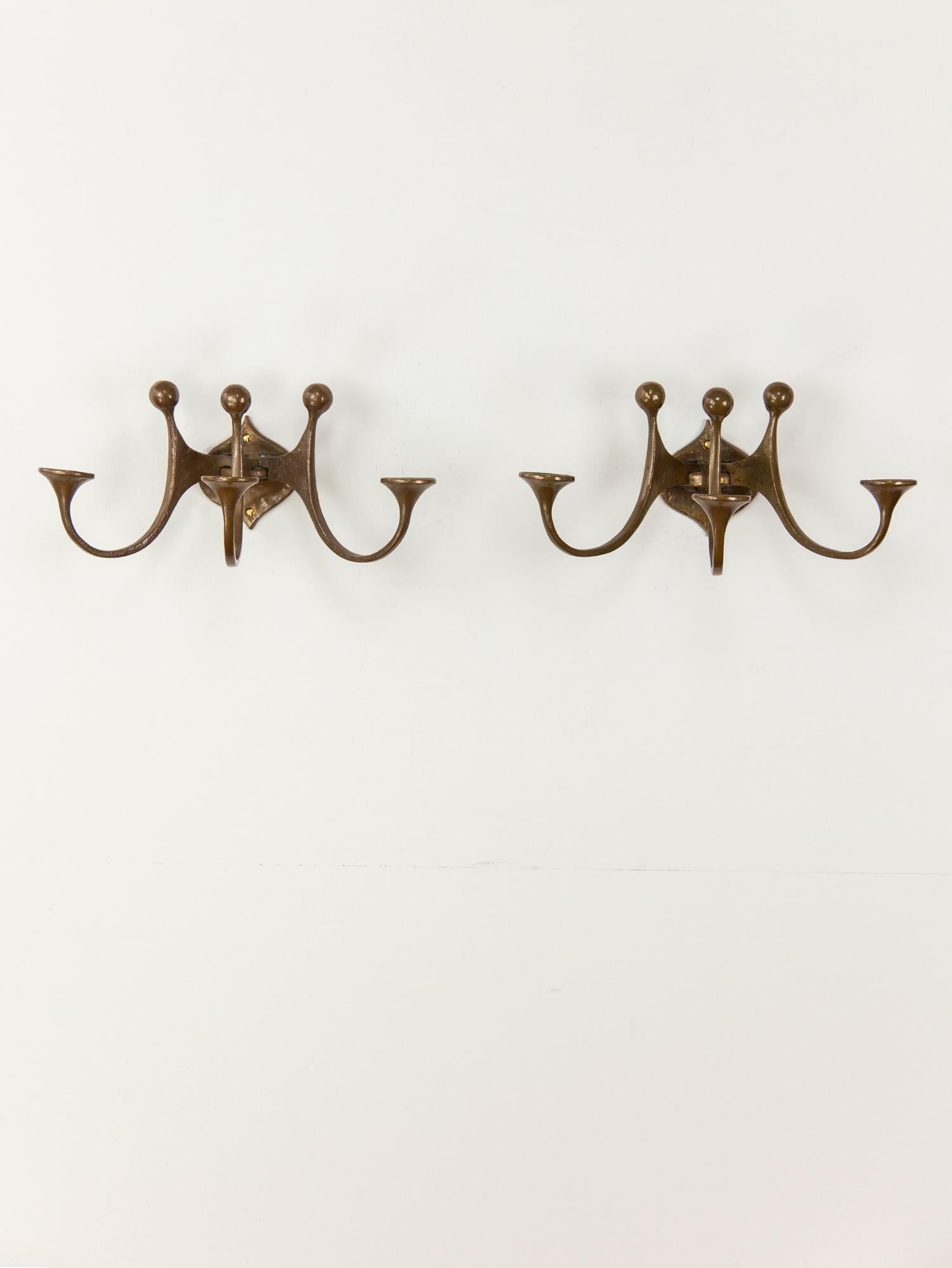Brutalist bronze sconces by Michael Harjes. The handmade sculptural sconces have a beautiful textural surface. Large in size the wall lights hold three candles each with a decorative arch finished with a playful spherical cap. Made in Germany, circa