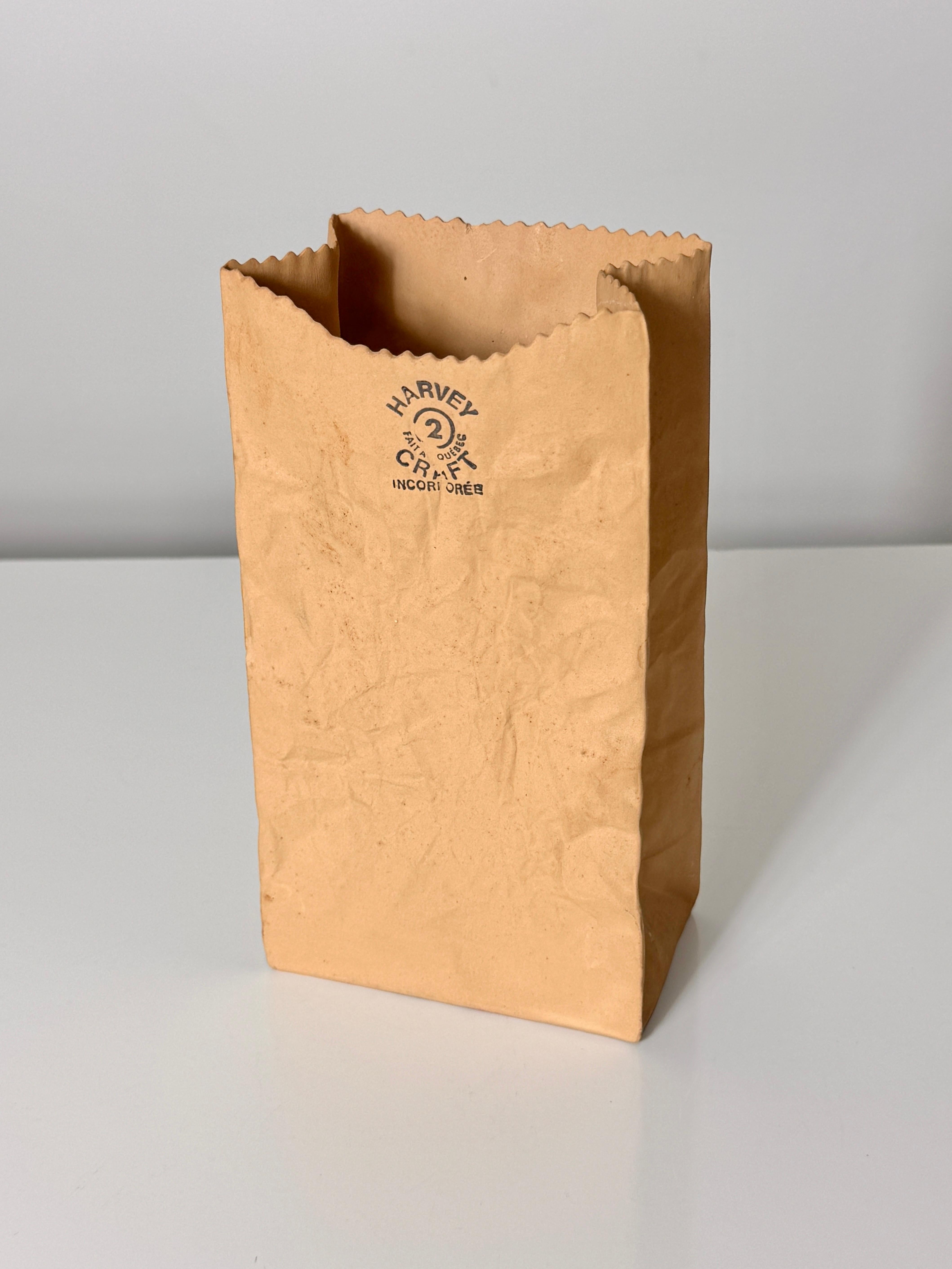 A crinkled ceramic paper bag vase designed by Michael Harvey circa 1970s

Unique pop art sculptural piece with incredible detail
Signed with stamp and sticker to underside 

4 inch width
2.375 inch depth
7.25 inch height