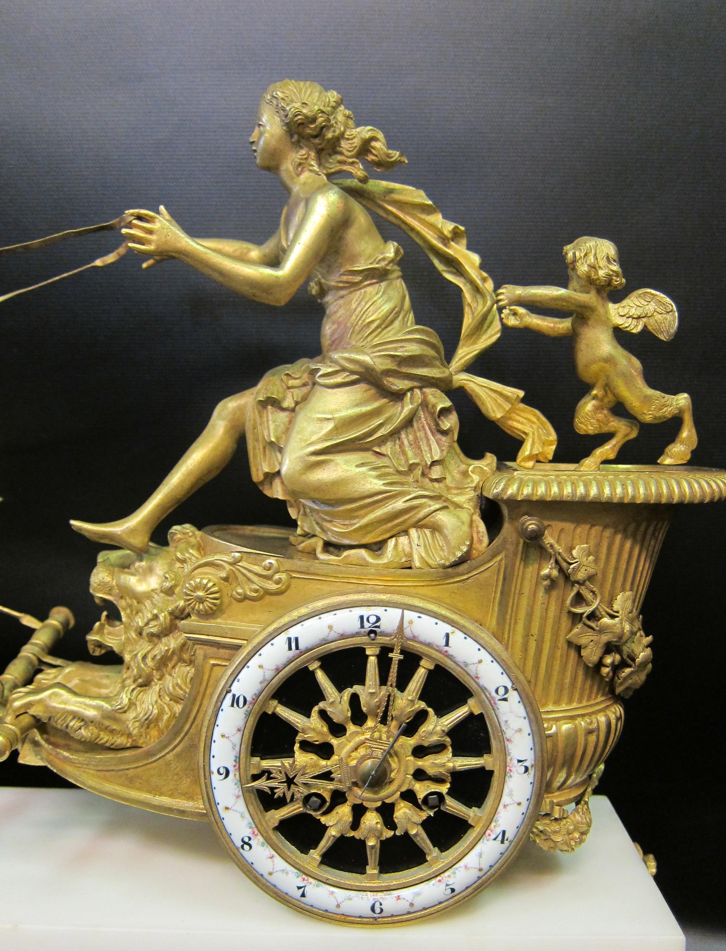This vintage, circa 1855, French Empire mantel clock is designed with a doré bronze mythological subject upon a footed white marble and gilt bronze platform. The mounted bronze sculpture is that of the goddess Aurora racing against time to chase the