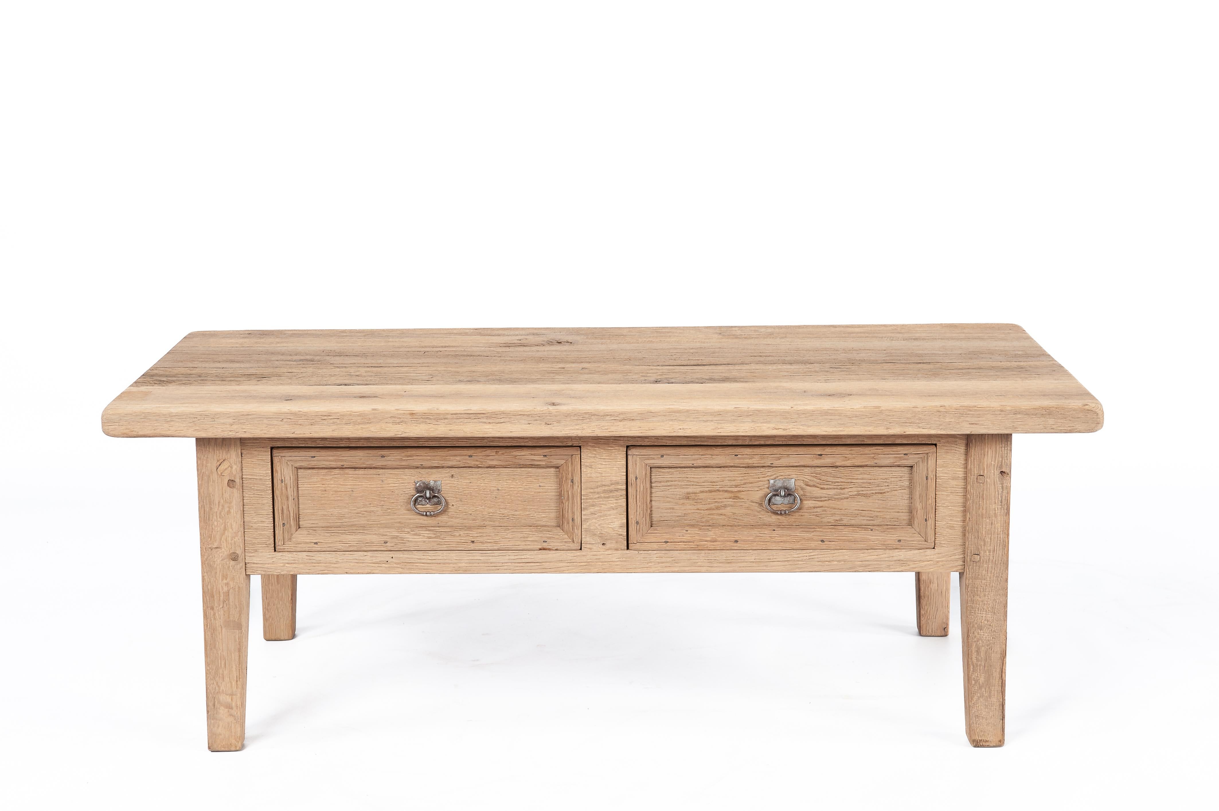 This is a timeless vintage coffee table, traditionally crafted from reclaimed oak wood dating back to the 1960s. This rustic piece was built by the esteemed Piet Rombouts & Sons furniture workshop, a legacy proudly continued by our family. The wood