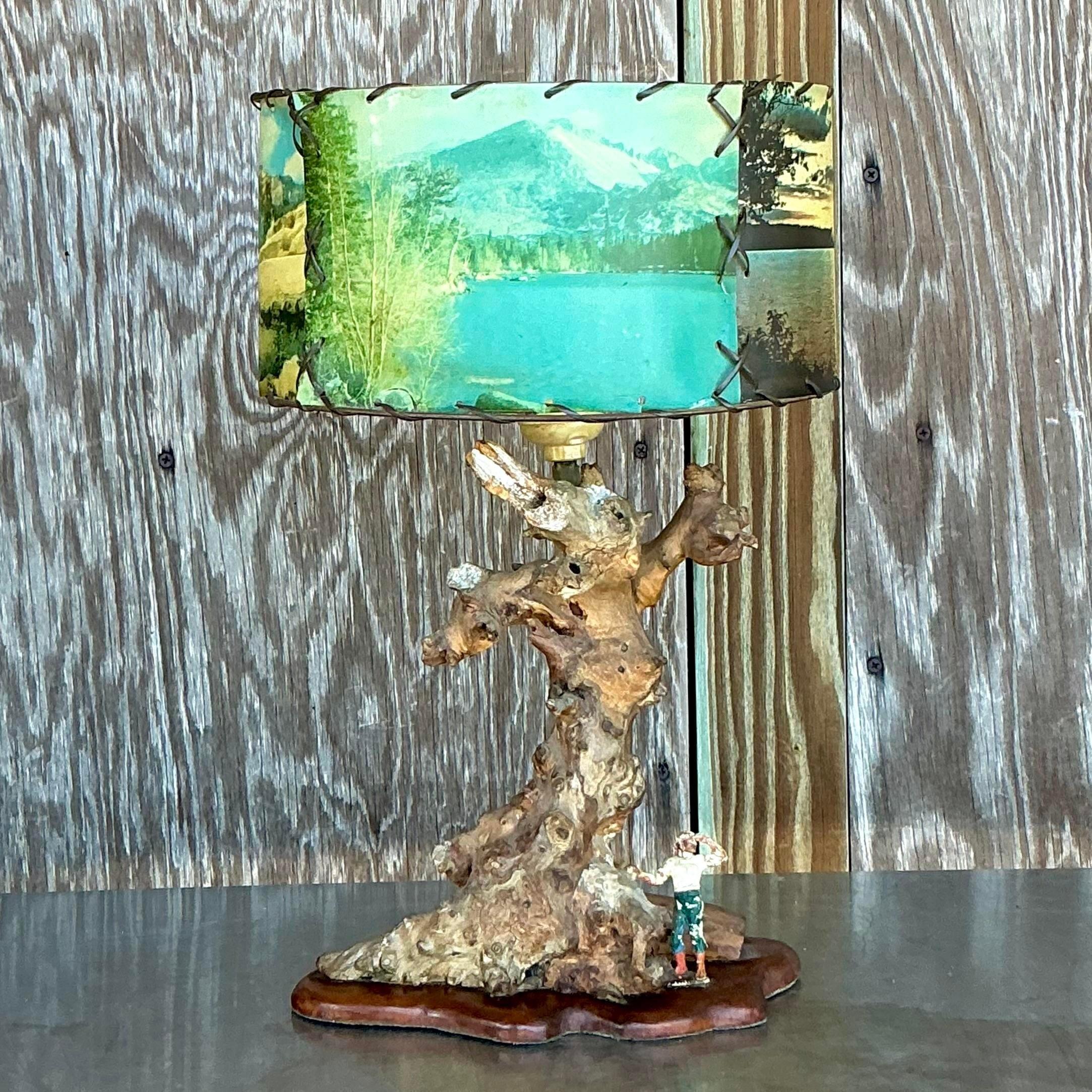 Illuminez votre espace avec la beauté naturelle de cette lampe Vintage MCM en bois flotté avec un abat-jour scénique. La base de la lampe est fabriquée à partir de bois flotté authentique, mettant en valeur les textures et les formes organiques du