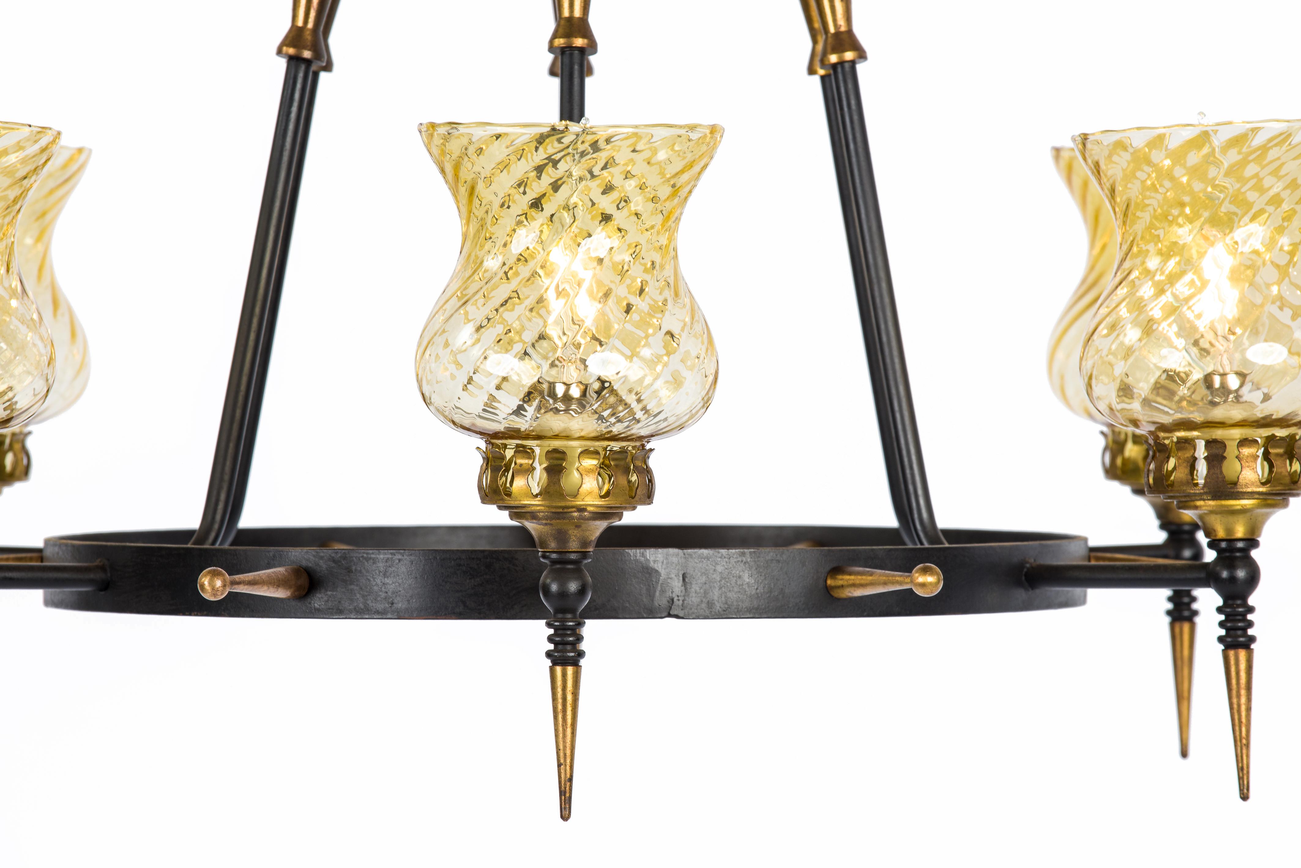 This elegant chandelier was made in France in the 1960s. It features a black patinated steel ring supporting 6 brass torches. The torches end with beautiful yellow twisted glass covers. This one-of-a-kind chandelier was made by a true craftsman and