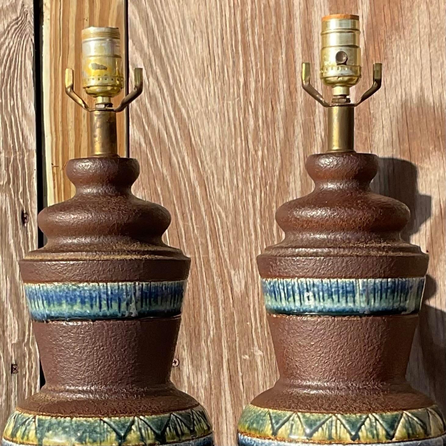 A stunning pair of vintage MCM table lamps. A chic combo of matte and gloss finishes with brilliant blue green bands. Rest of brass plinths. Acquired from a Palm Beach estate.