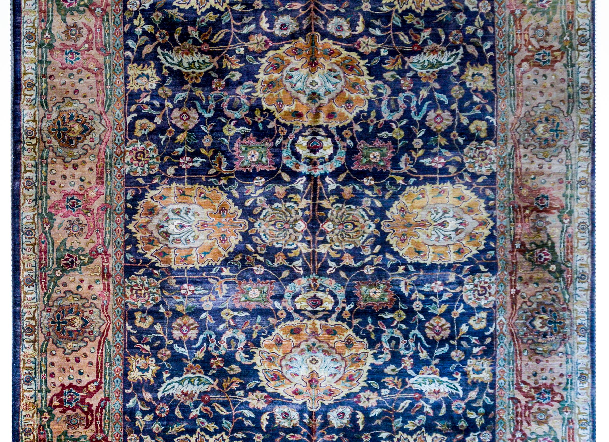 A fantastic mid-20th century Indian Sultanabad style rug with a beautiful large-scale mirrored floral pattern with four large medallions amidst scrolling vines and myriad flowers on a dark indigo background. The border is really wide with a