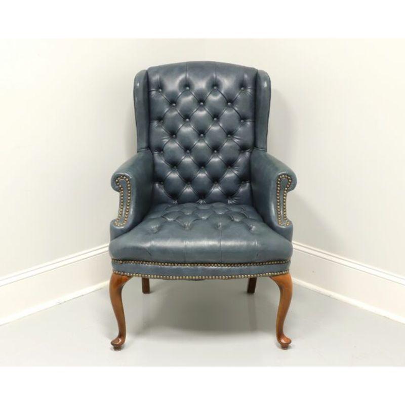 A Queen Anne style wing chair, unbranded, similar quality to Hickory Chair or Hancock & Moore. Cherry wood frame with blue leather upholstery. Button tufted with brass nailhead trim, rolled arms, cabriole front legs and pad feet. Likely made in the