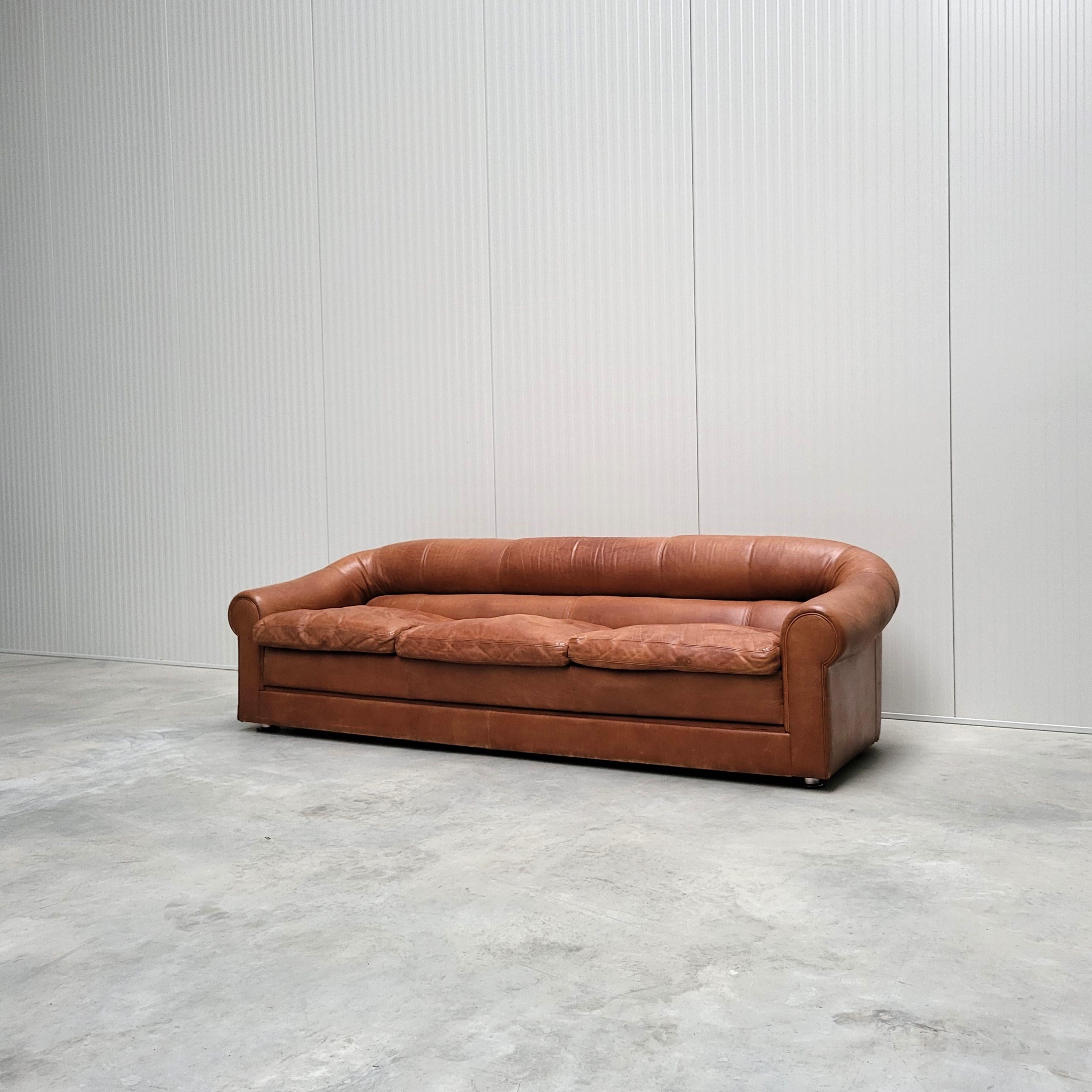 Dieses zeitlose, ikonische Sofa wurde in den 1970er Jahren in Italien nach dem Vorbild von Poltrona Frau oder De Sede hergestellt. 

Das Sofa ist mit einem erstaunlich glatten, mittelbraunen Leder gepolstert. 
Die Kissen sind mit Entenfedern