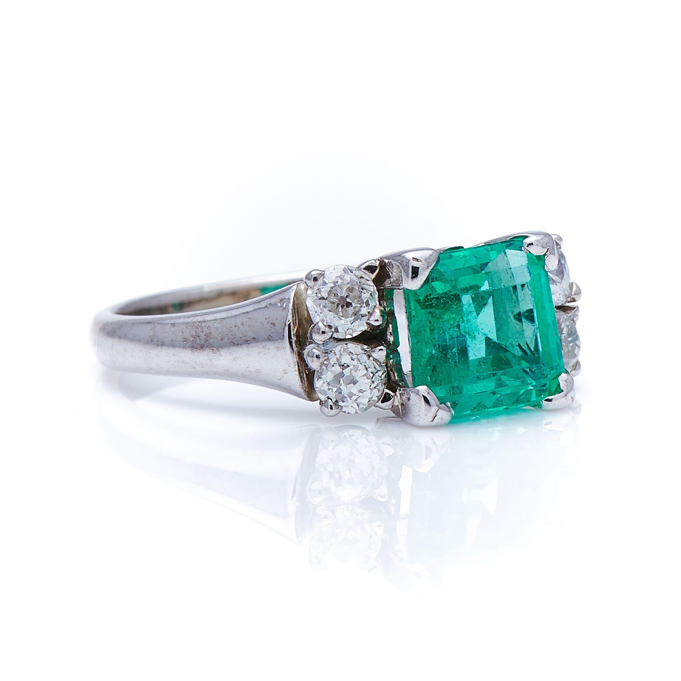 Emerald and diamond ring, mid 20th century. This ring is set with an unusually clean Colombian emerald in a bright, fresh green colour, between shoulders set with early 20thcentury circular-cut diamonds. The claw setting is simple and effective,