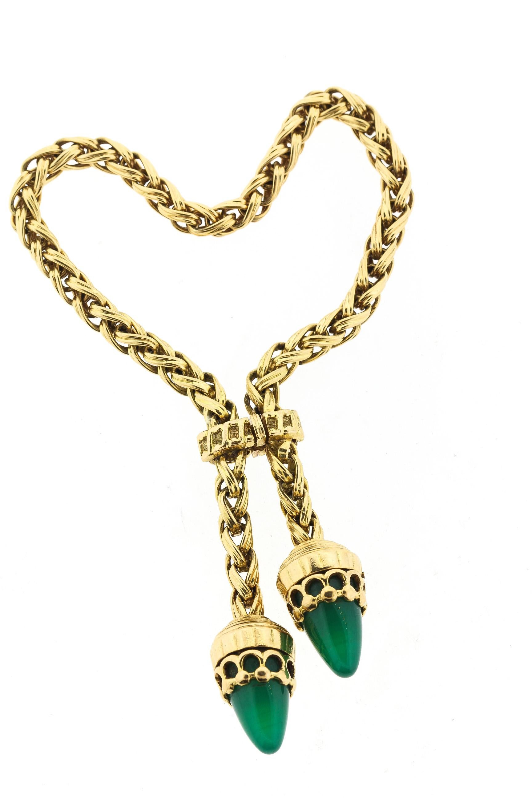 A chic vintage 18k yellow gold woven rope tassel bracelet suspending two dart shaped chalcedony, circa 1960. This unique design clasps around the hand and dangles the two green stones. The woven gold is of beautiful construction. The bracelet