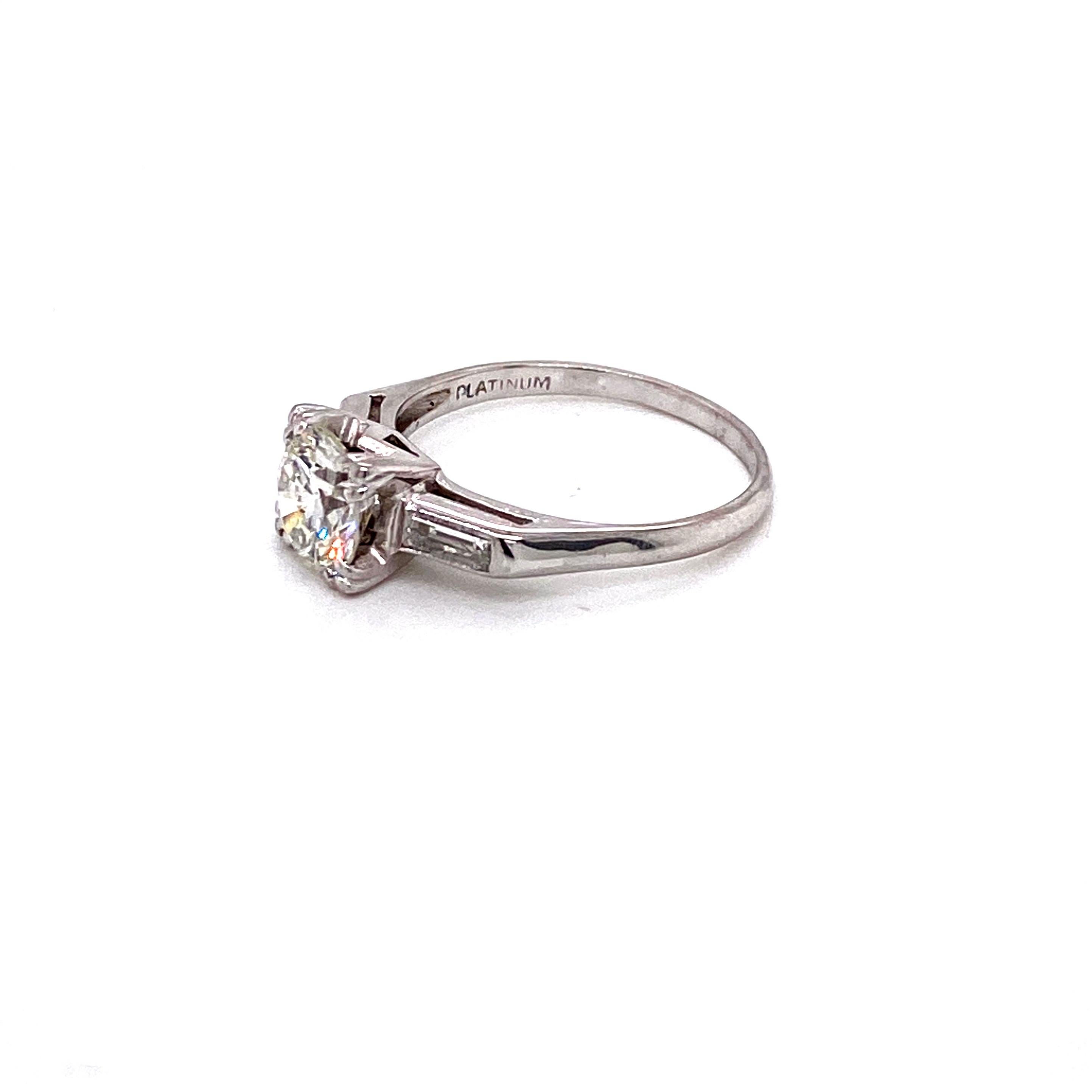 A breathtaking exemplar of mid-20th century elegance, this vintage platinum ring dates back to the iconic 1950s. The showstopping centerpiece is a gorgeous round transitional cut diamond weighing approximately 1.15 carats. Glowing with a warm J