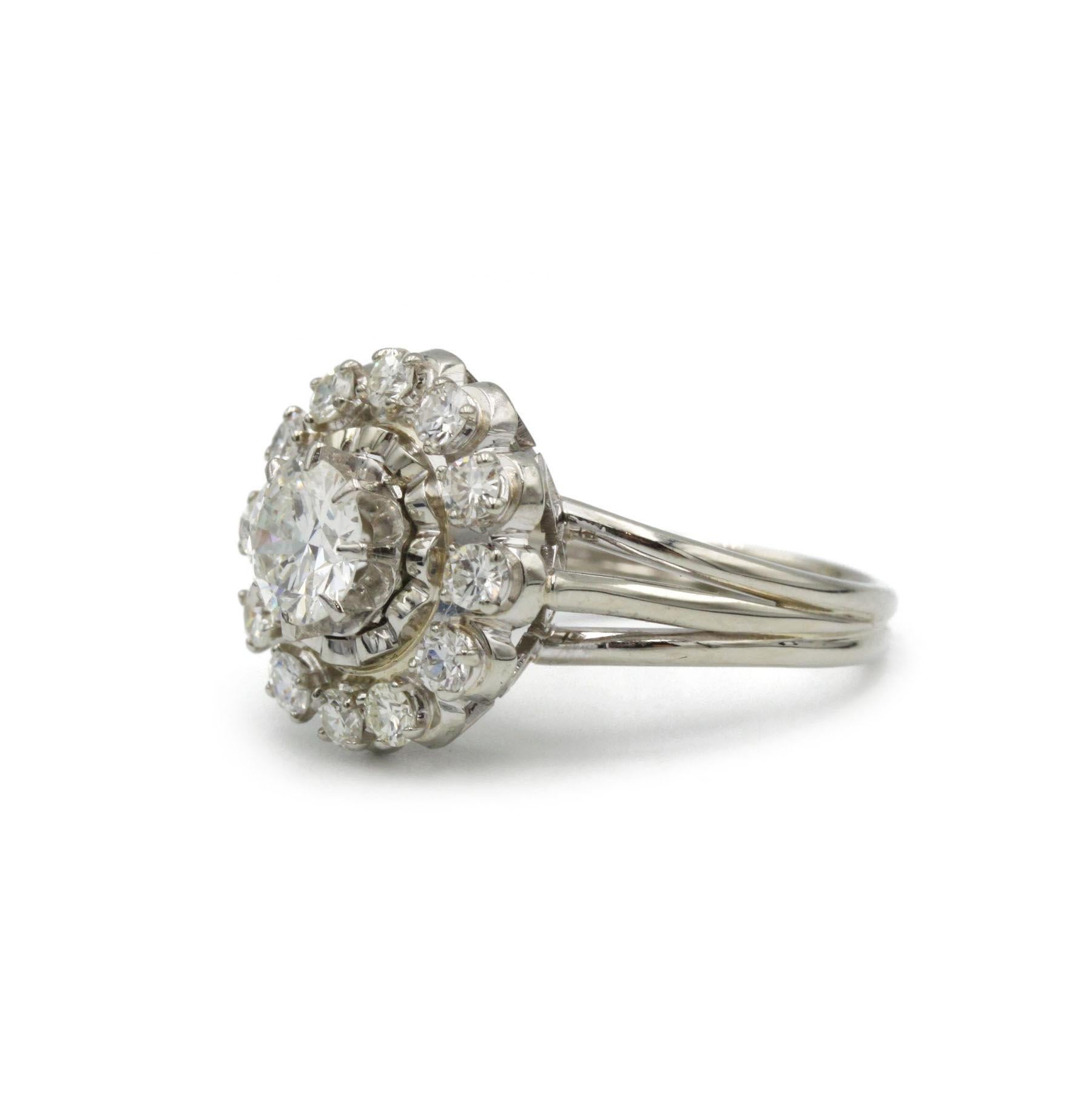 Squisito anello francese della metà del XX secolo, questo pezzo vintage a grappolo presenta un diamante rotondo brillante da 0,80 carati nel cuore, circondato da un'aureola di 12 diamanti rotondi più piccoli (circa 0,30 carati in totale). Realizzata