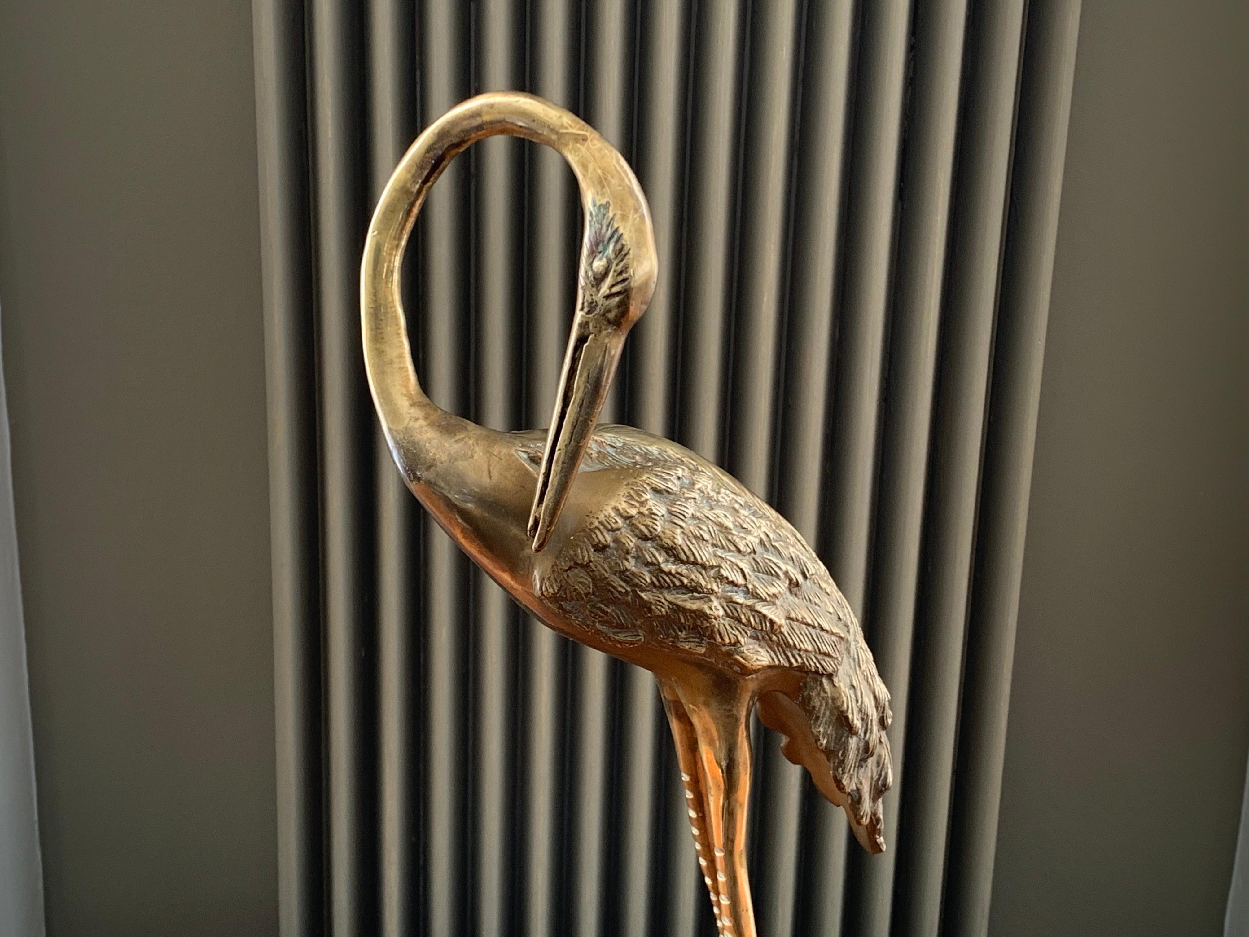 Vintage 1970s brass crane with a curved neck and sculpted plume of feathers. The crane is stood on a rectangular base to help keep it stable and upright. In excellent vintage condition with a deep, aged patina. An interesting and decorative piece