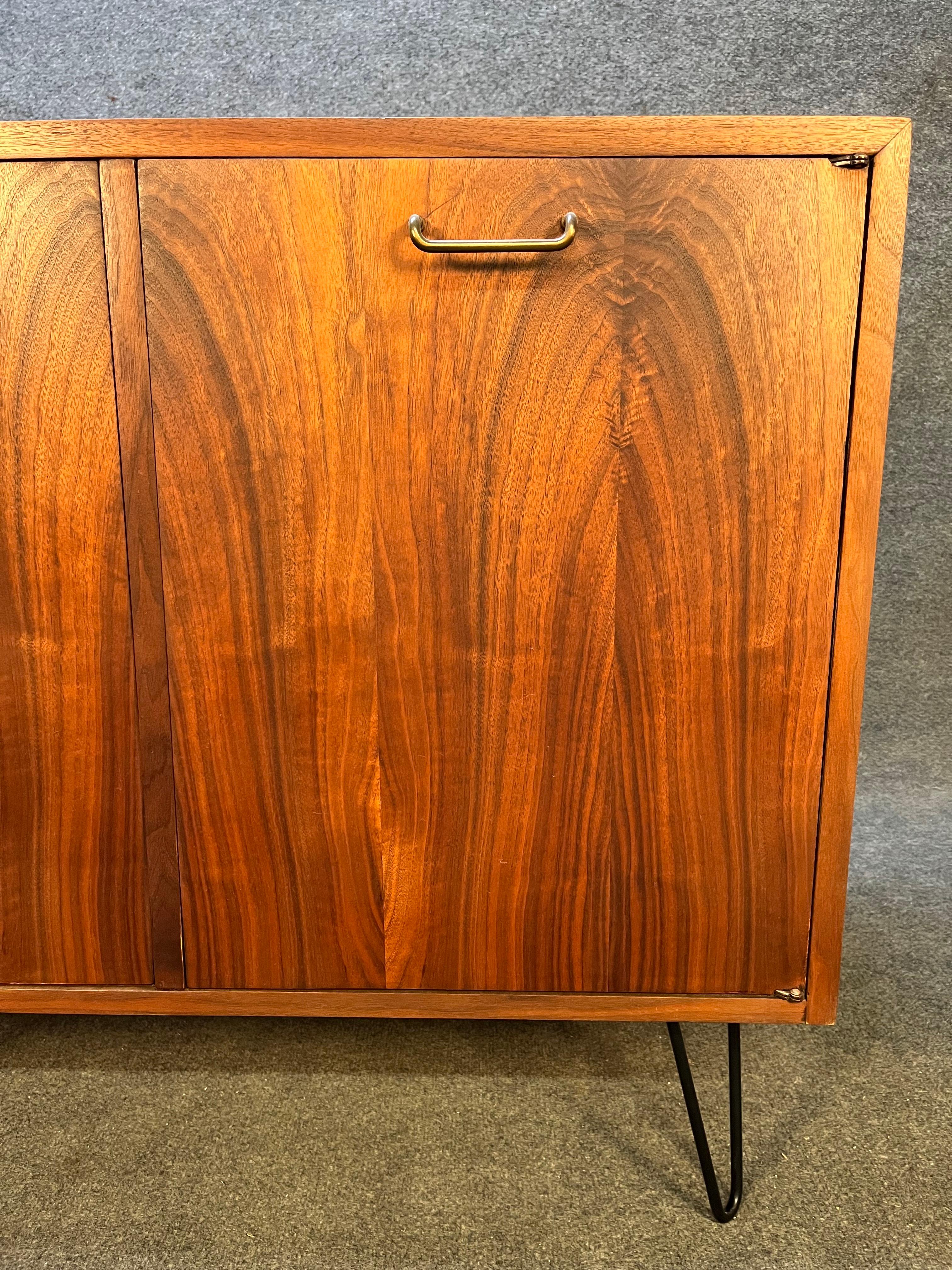 Vintage mid century storage cabinet by American of Martinsville. Versatile piece that would be good for storage, entryway storage and storage for some of your vinyl records. Doors open to two white drawers and storage cubbies. Beautiful black walnut