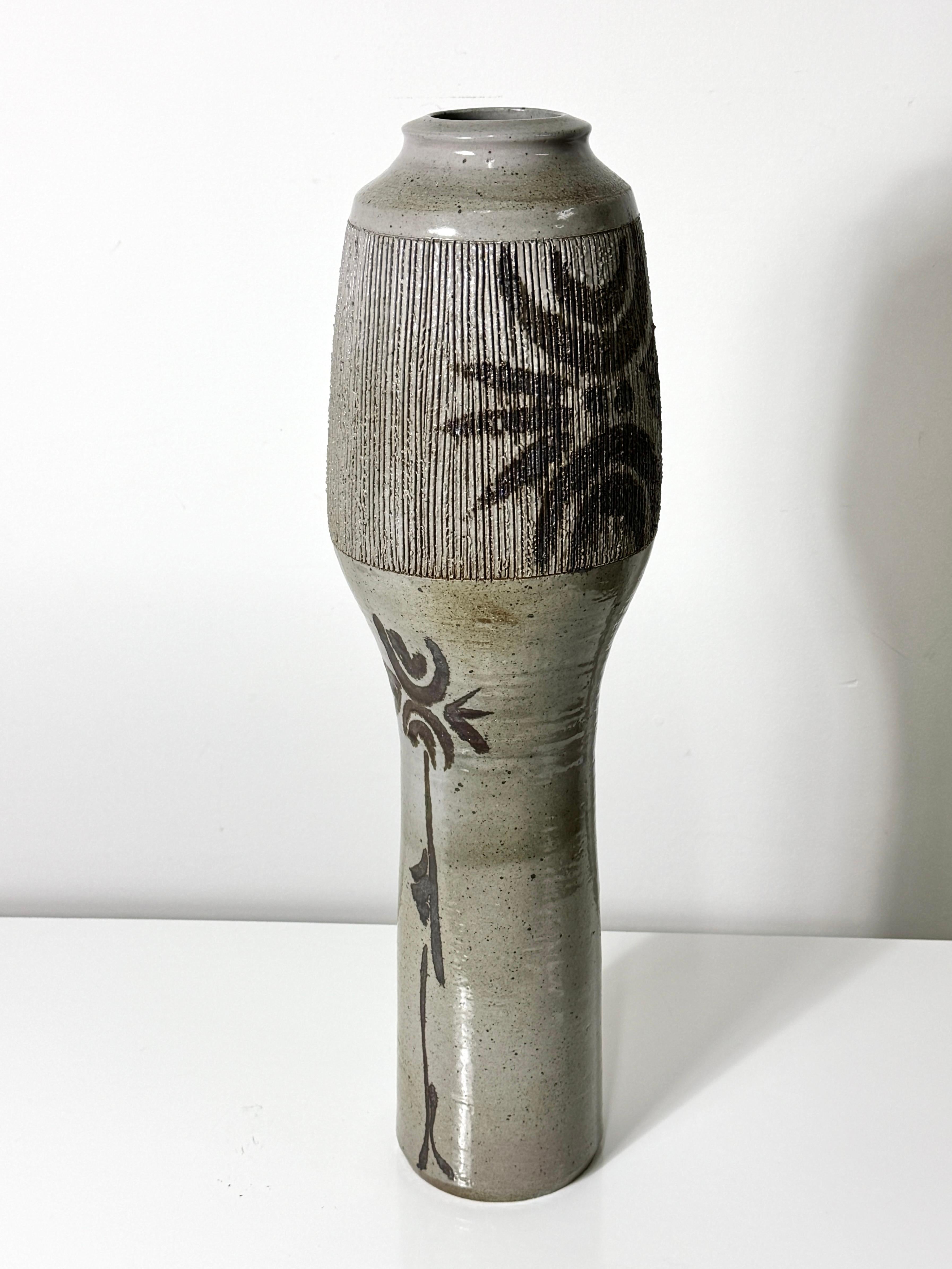 Tall ceramic floor vase by Sheniar Abdullah Salman circa 1970s
Organic form in gray glazed stoneware with incised upper detailing and applied modernist decoration.

27 inches in height
7.5 inch diameter at widest

With an MFA in fine arts from