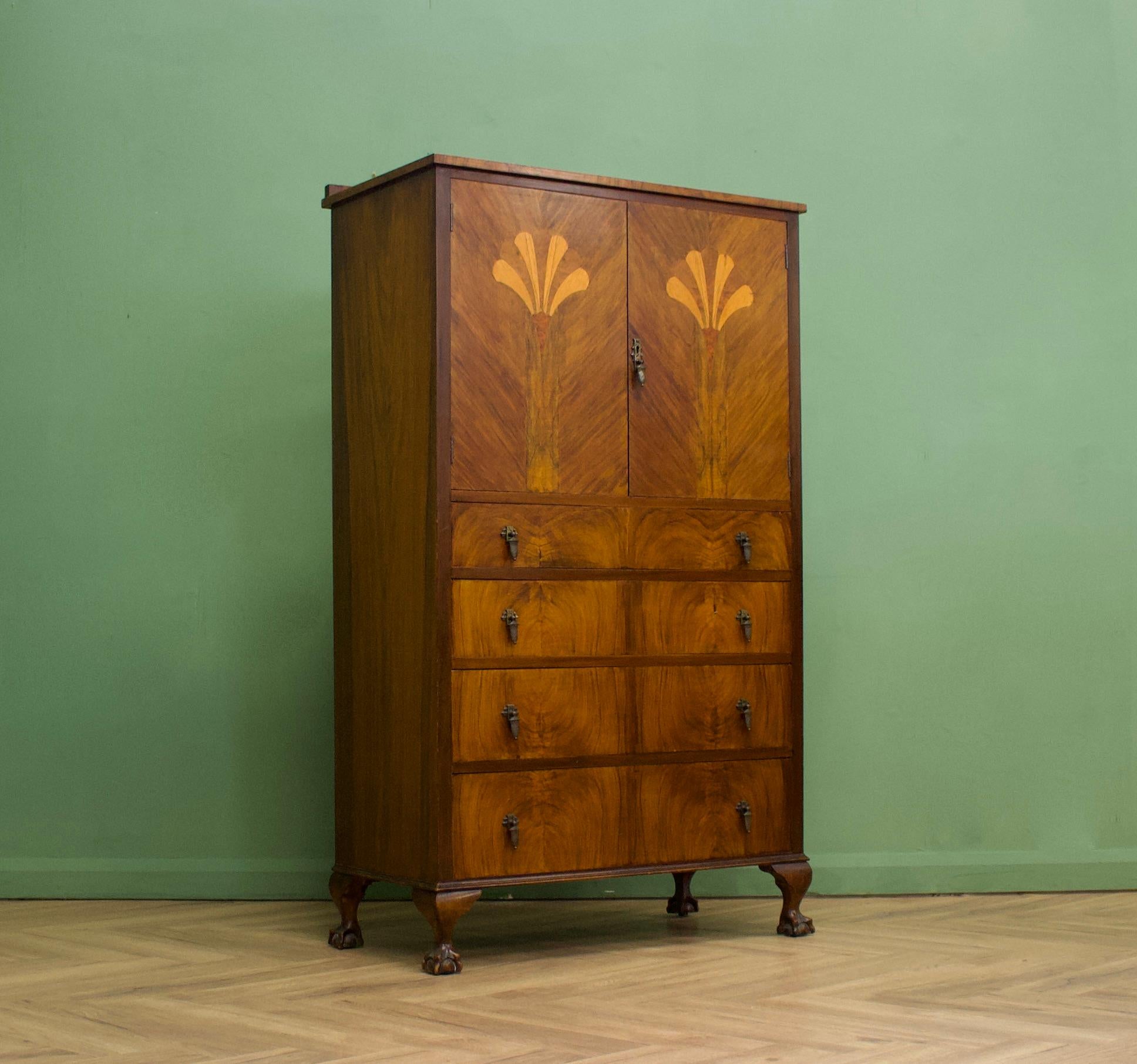 A vintage 1930s Art Deco linen cabinet / tallboy, featuring marquetry inlaid with walnut veneers
There is a cupboard with a shelf and four drawers