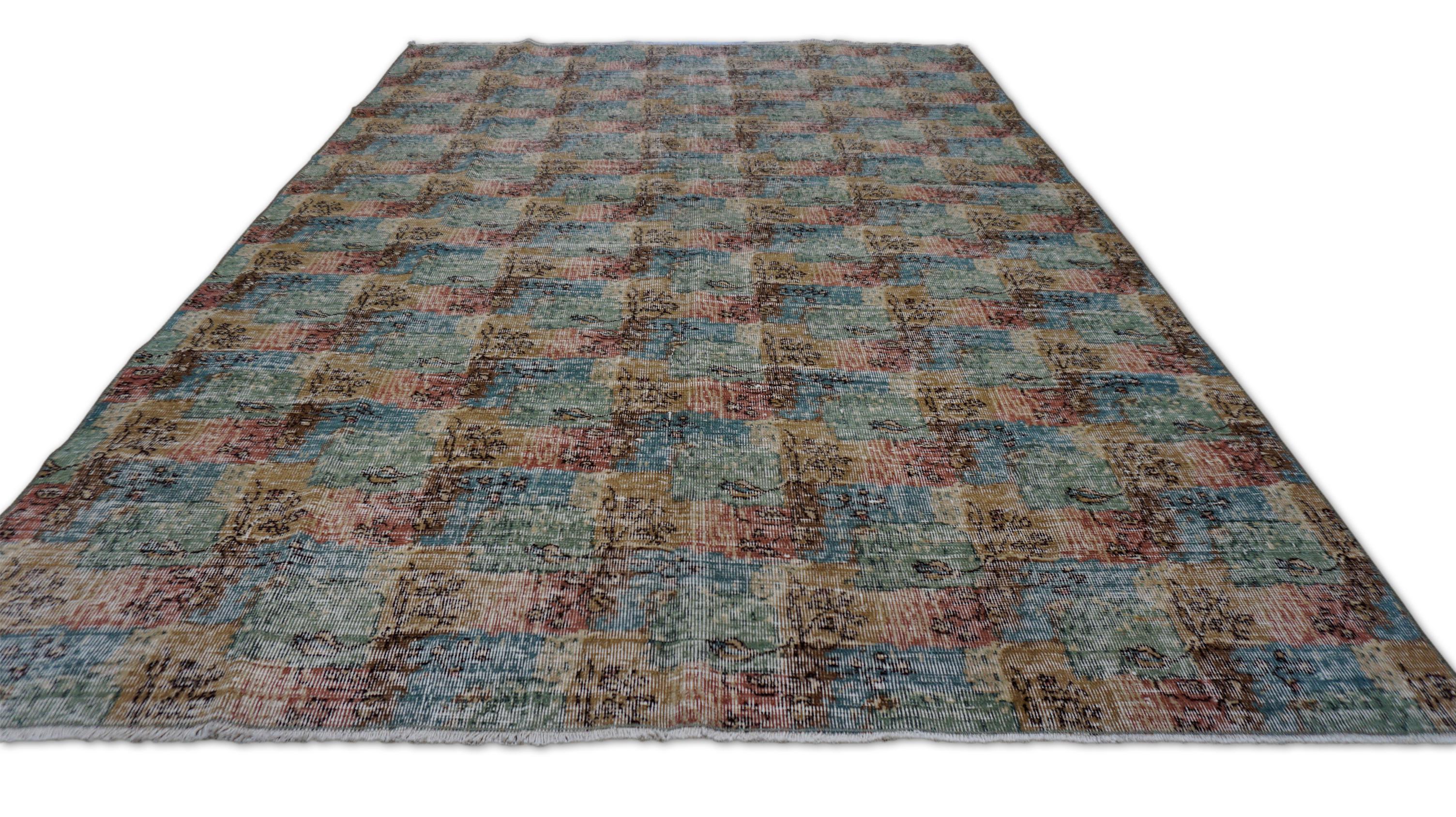 Questo tappeto in lana annodato a mano è caratterizzato da un disegno a scacchiera morbidamente astratto, reso in tenui tonalità della terra - verde muschio, rosso, avorio e beige sabbia - che crea un gioco armonico e testuale sul campo. Il motivo