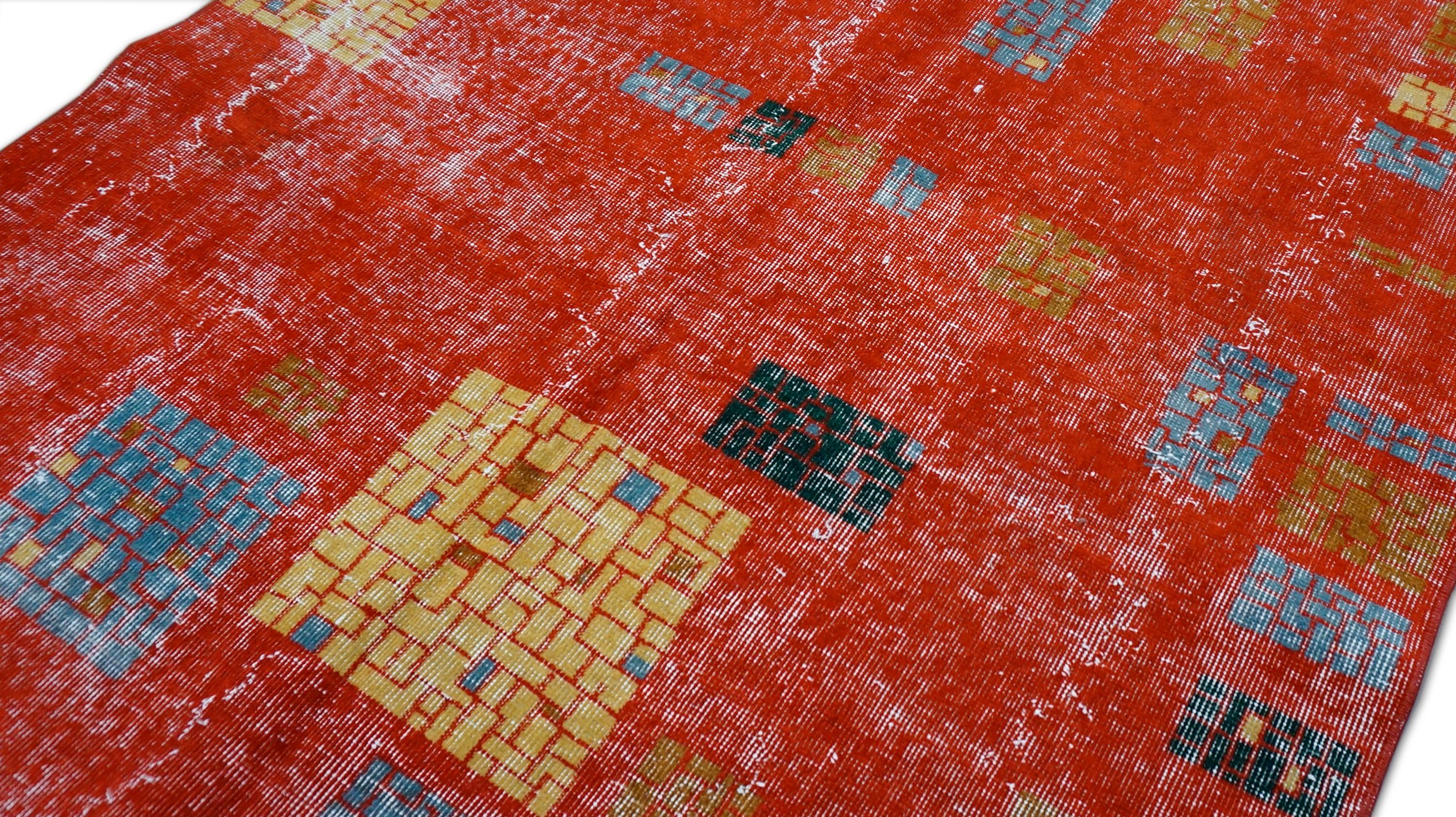This vibrant hand-knotted wool rug features a bold and contemporary aesthetic with a playful mosaic motif scattered across a saturated red field. Handcrafted by skilled artisans, the rug juxtaposes abstract square and rectangular patterns in orange,