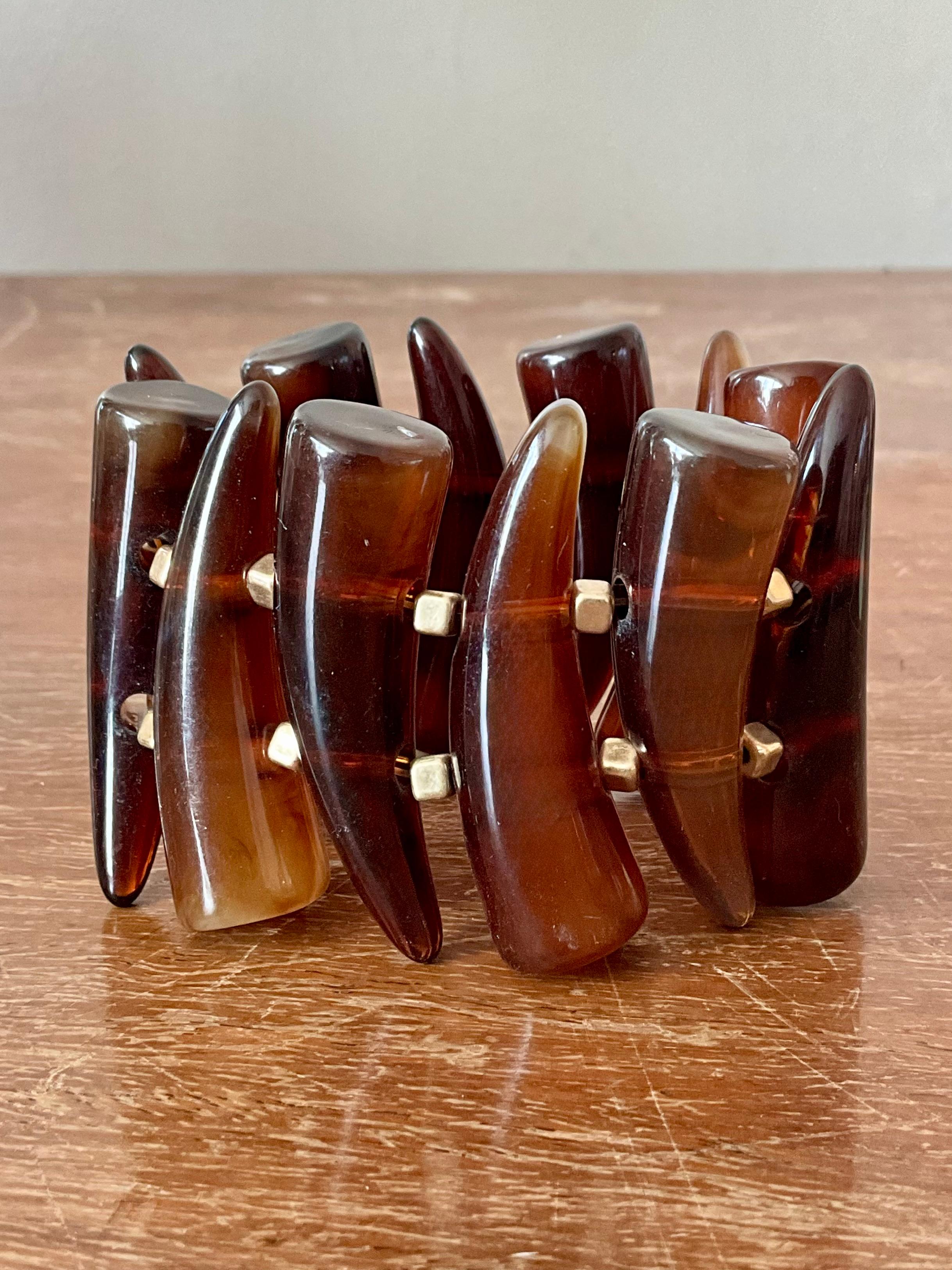 Questo braccialetto elastico vintage in bachelite a forma di corno è un esempio straordinario di design di metà secolo. Realizzato in autentica bachelite, un materiale plastico molto diffuso tra gli anni '30 e '50, il bracciale è caratterizzato da