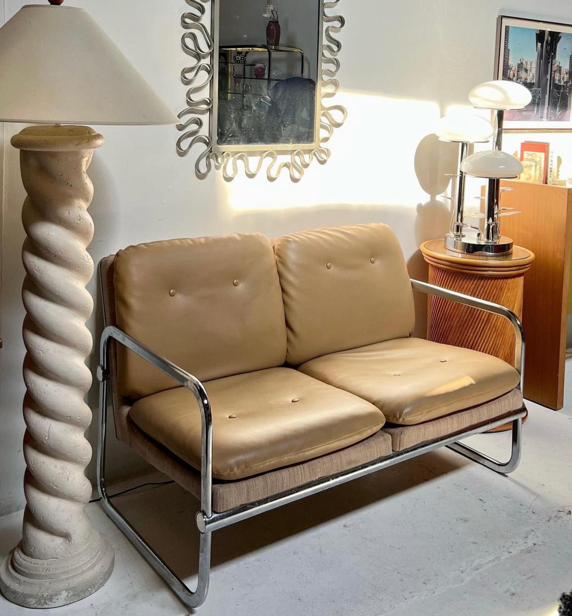 This Mid-Century Modern 2 seater is just as comfortable as it is stylish. The geometric frame is made of chrome plated tubular steel quintessential to the bauhaus design. The seat and backrest are upholstered with beige faux leather and a basket