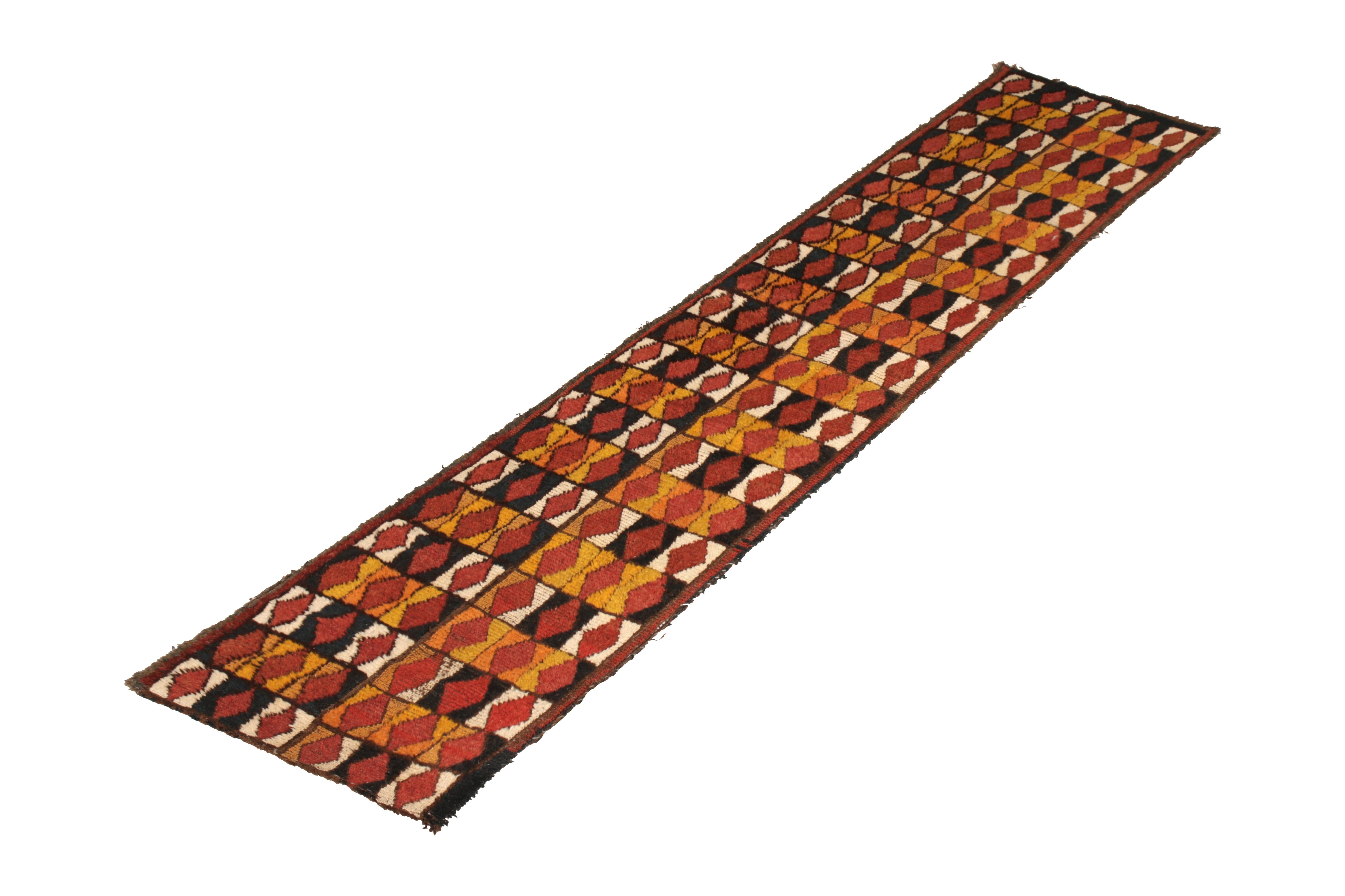 A rare vintage rug originating from Iraq, this midcentury runner features a geometric pattern inspired by Moroccan style rug patterns. Hand knotted, circa 1950-1960 comprising wool in beige, orange, red, black, brown, and yellow, this particular