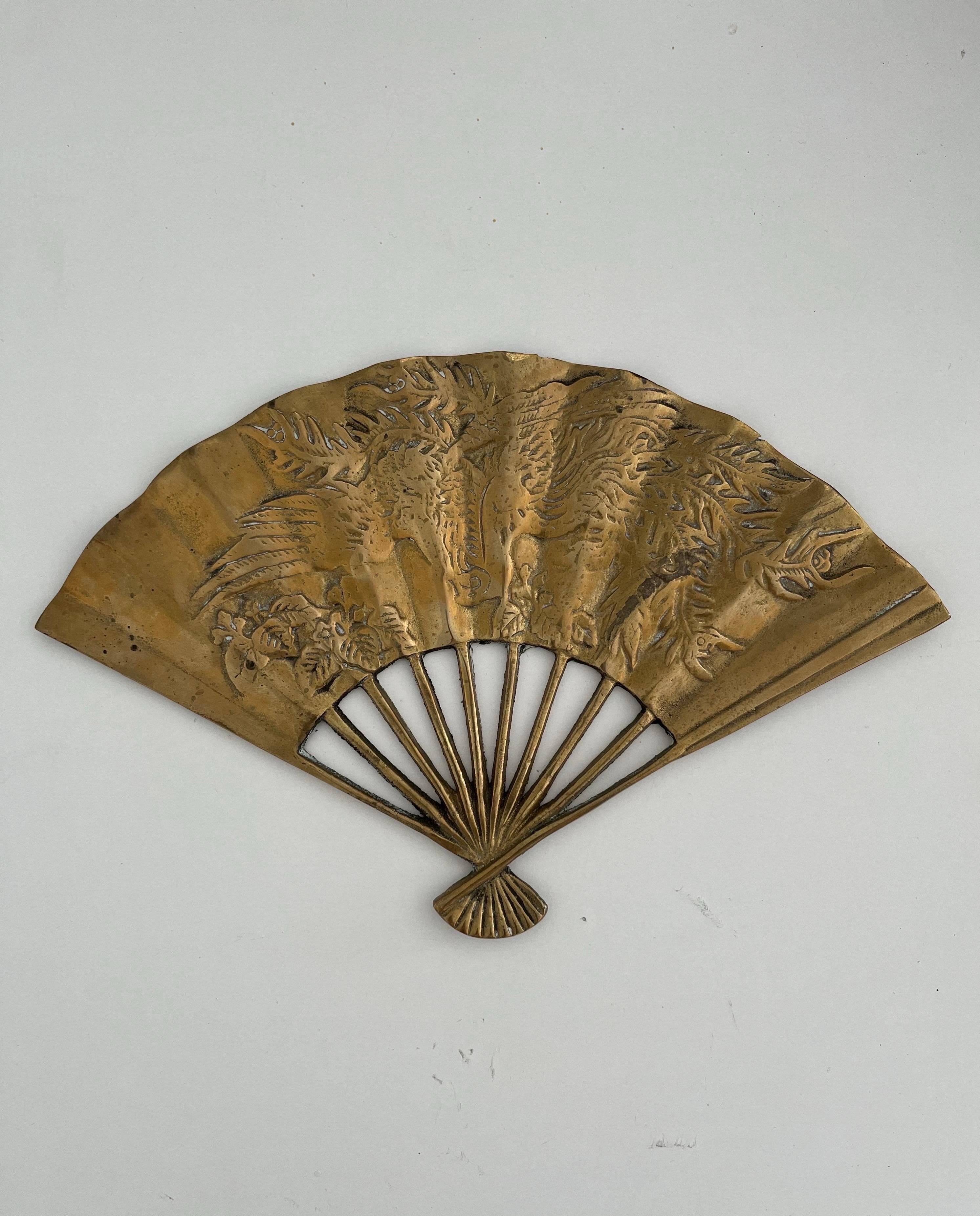Vintage Carved Brass Asian Inspired Fan Wall Hanging or Paperweight 
Solid sturdy piece, in great vintage condition. Some patina to the back side 
Intricately carved florals and dragon phoenix design. Accordion style fan, great wall hanging or